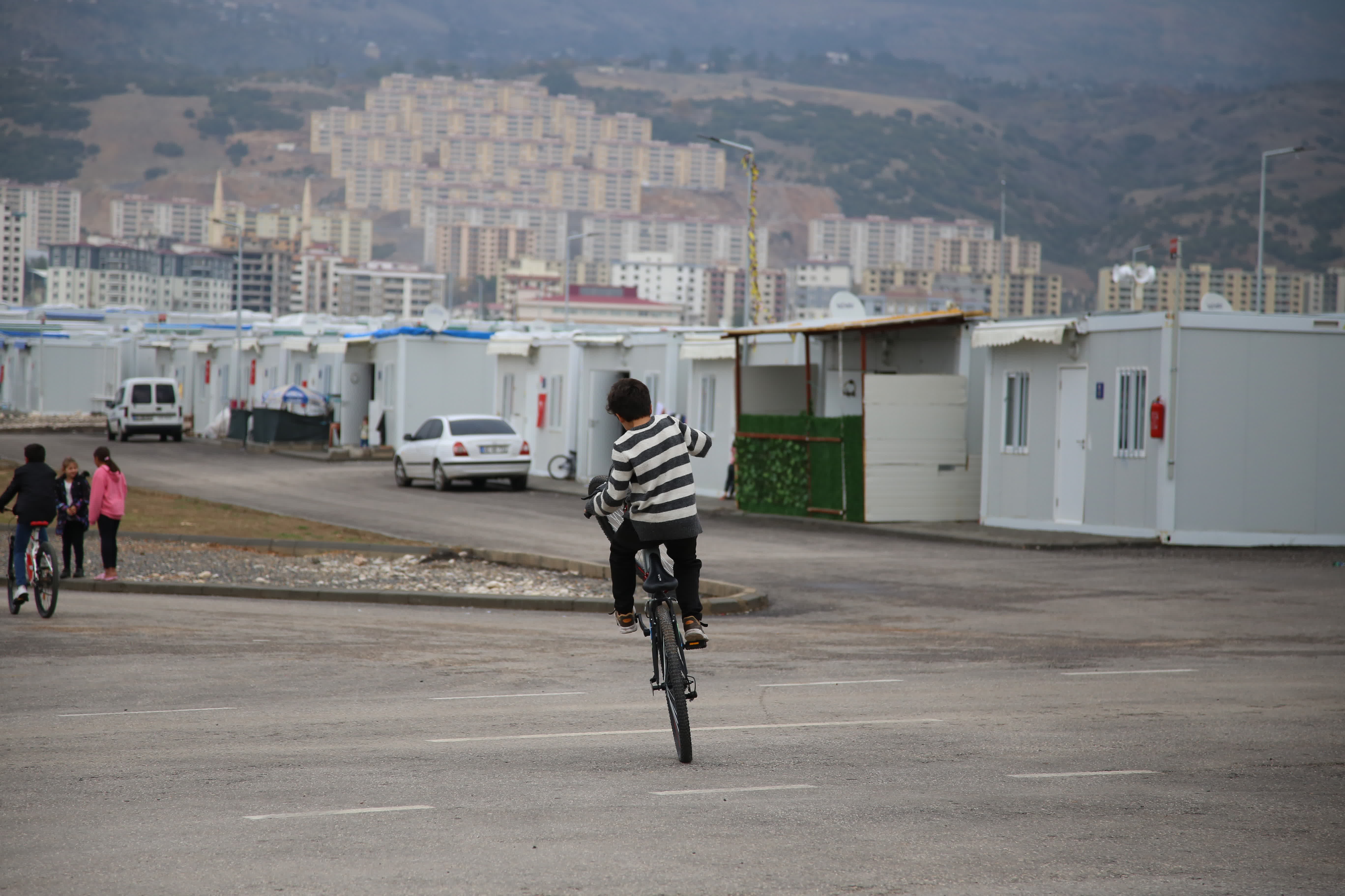 12月6日，在土耳其卡赫拉曼馬拉什，一名男孩在「集裝箱社區」內騎自行車。（新華社）