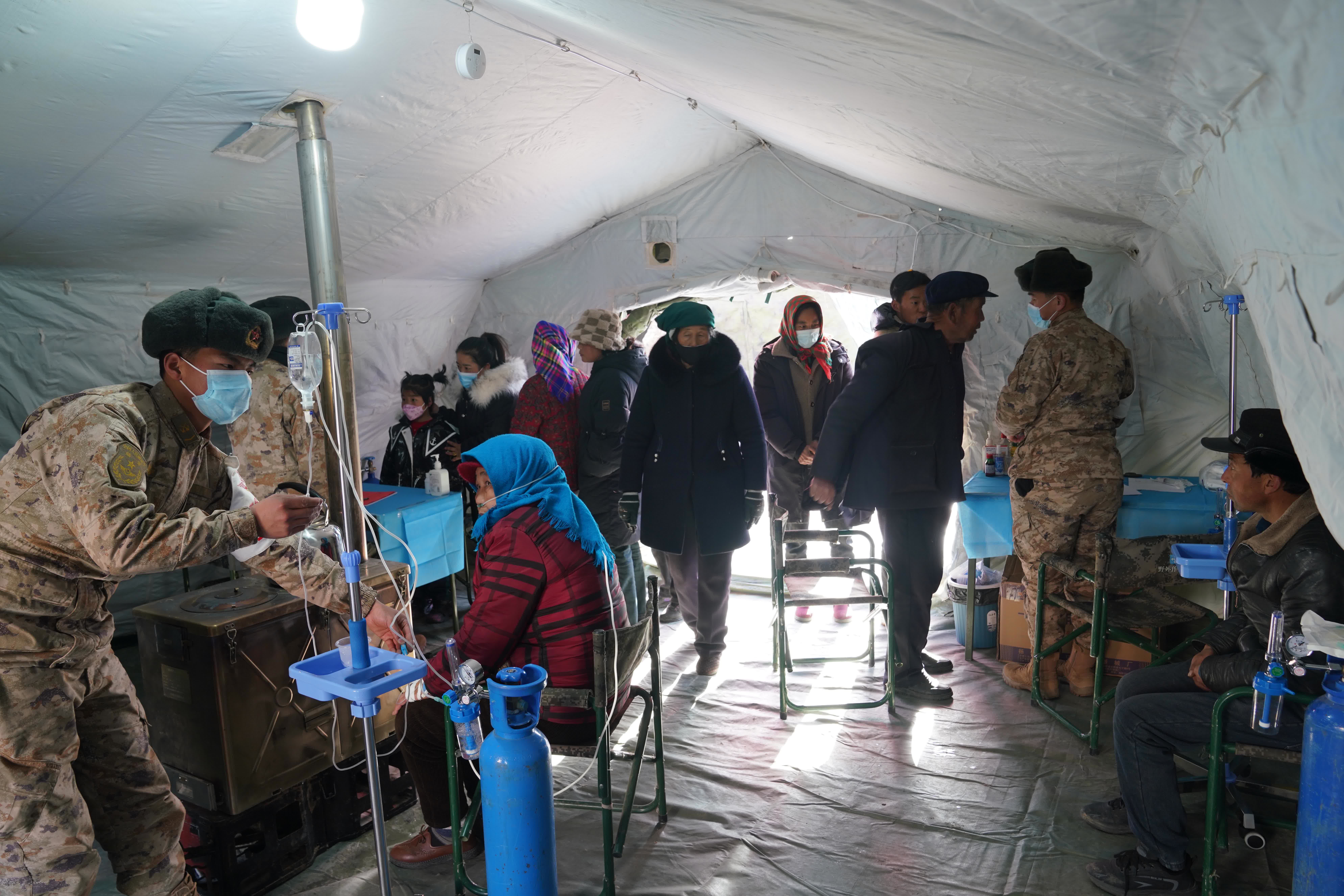 12月20日，陸軍第76集團軍某旅官兵在積石山縣石塬鎮安置點為受災群眾提供醫療服務。（新華社）