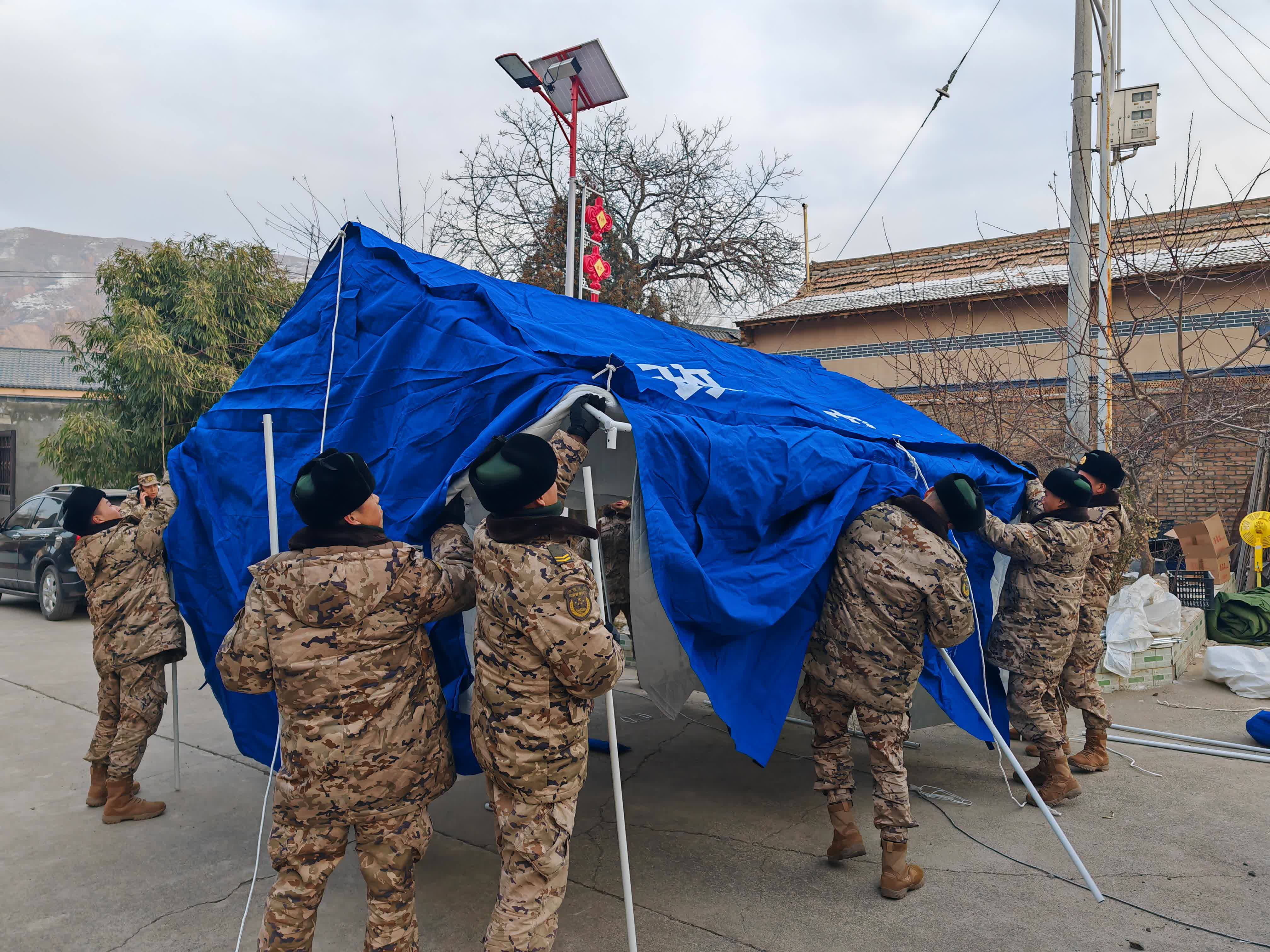 12月20日，武警甘肅總隊臨夏支隊官兵在積石山縣劉集鄉高李村搭建帳篷。（新華社）
