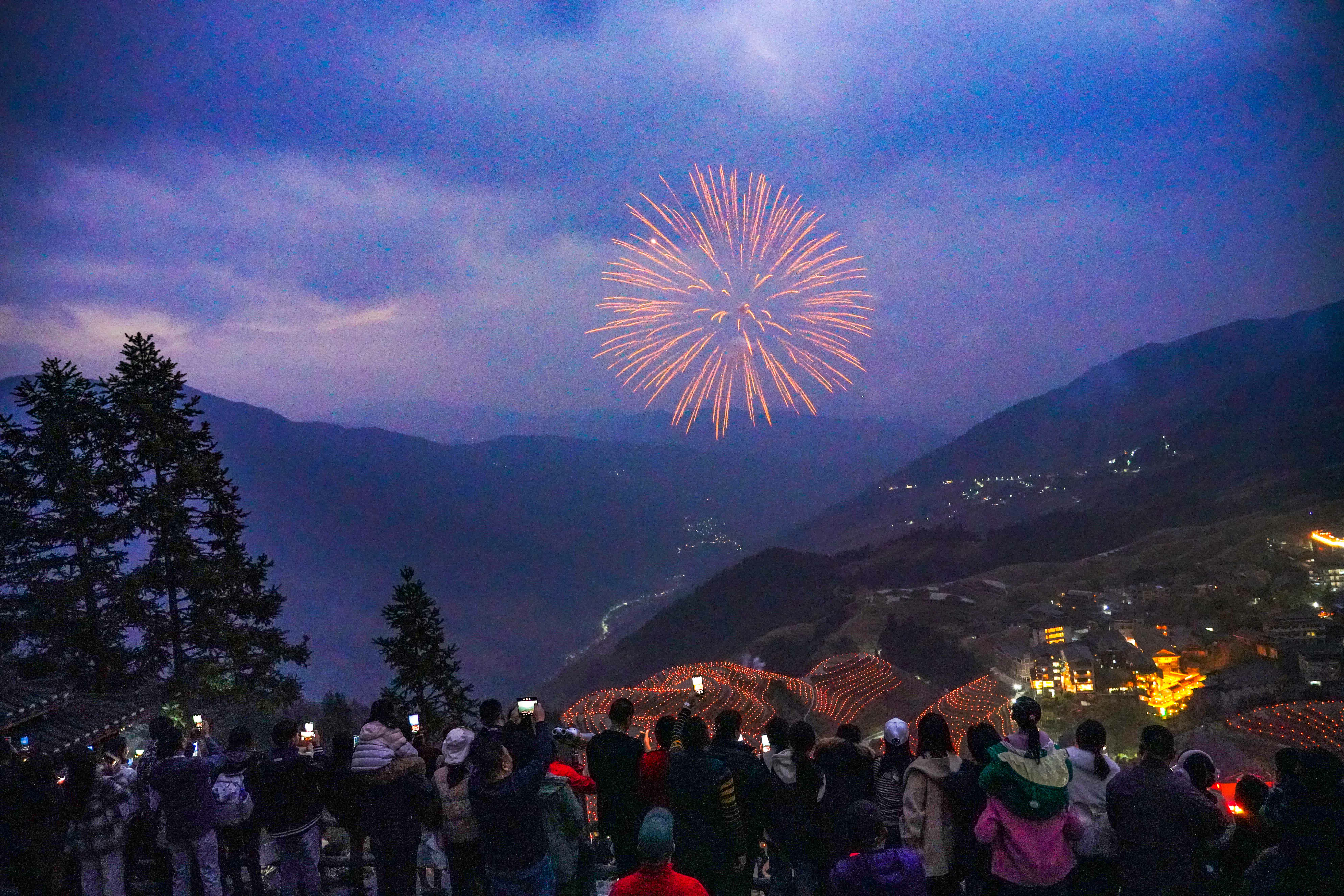 2023年12月31日傍晚，在廣西桂林市龍勝各族自治縣龍脊鎮平安村，遊客在觀賞梯田煙花美景。（新華社）