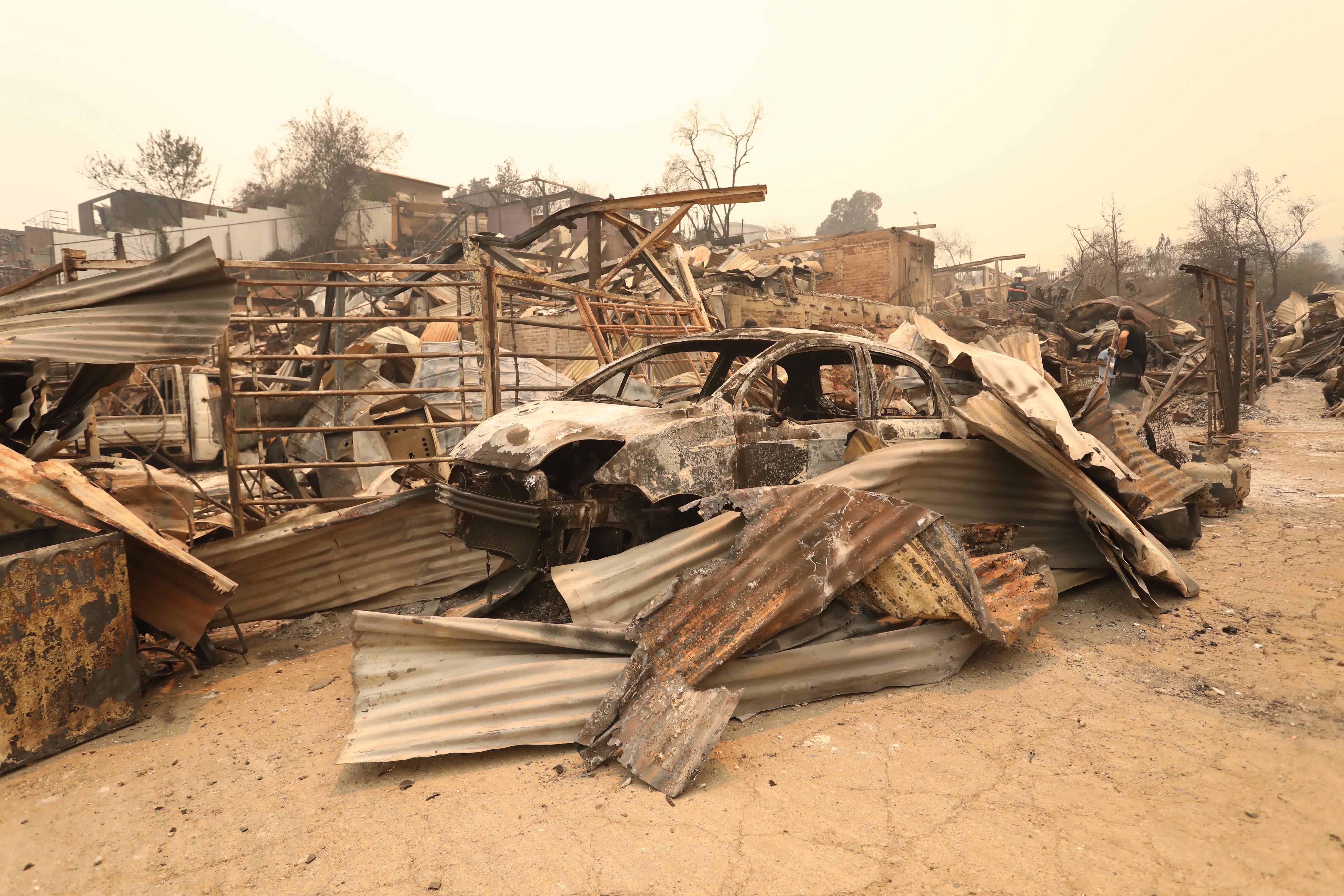 這是2月3日在智利瓦爾帕萊索大區比尼亞德爾馬市拍攝的在森林火災中燒燬的房屋和汽車。（新華社）