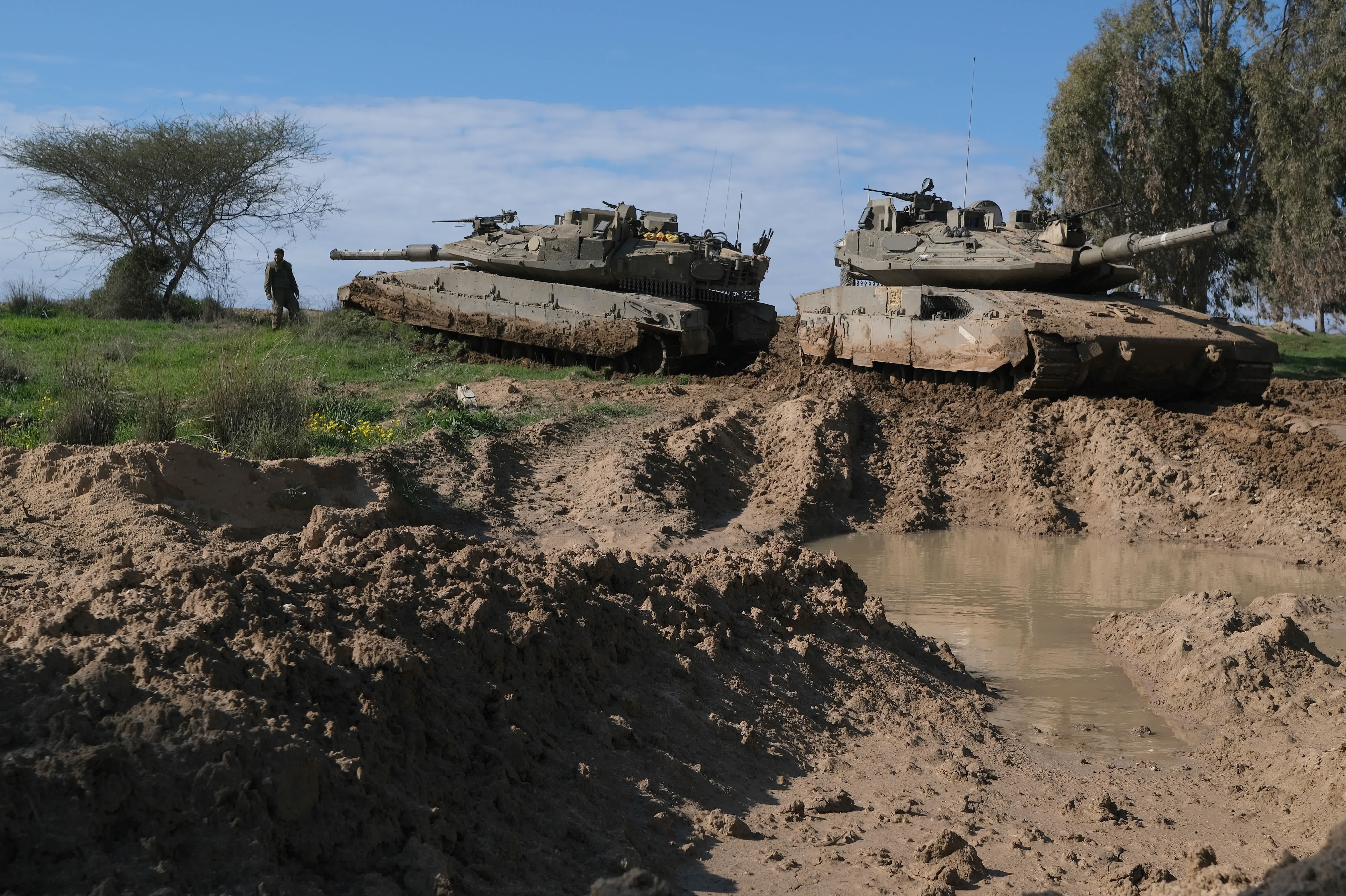 2月5日，在加沙邊境以色列一側，一名以軍士兵站在坦克旁。（新華社）