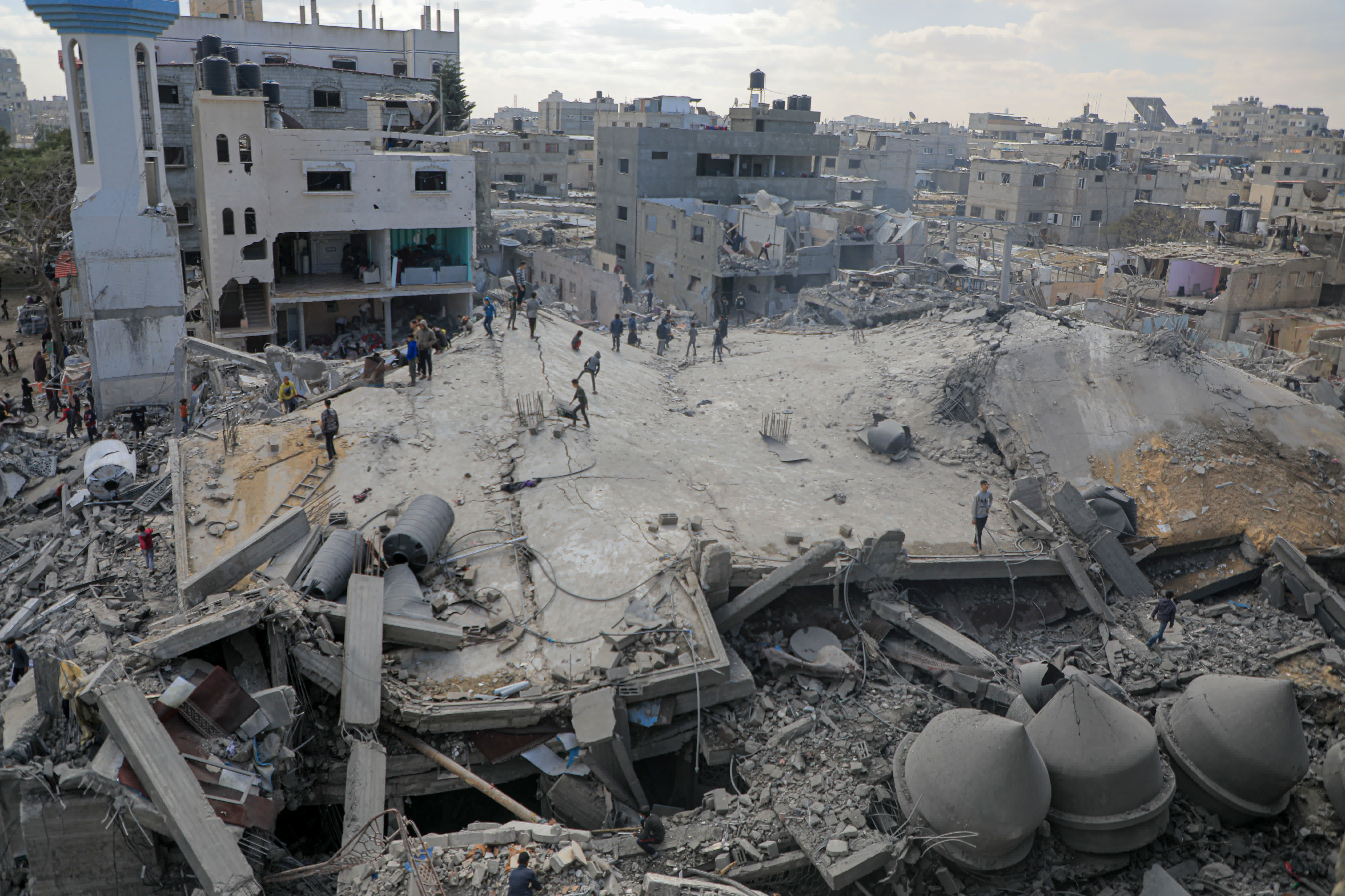 2月22日，人們查看加沙地帶南部城市拉法一處以軍襲擊後的建築廢墟。（新華社）