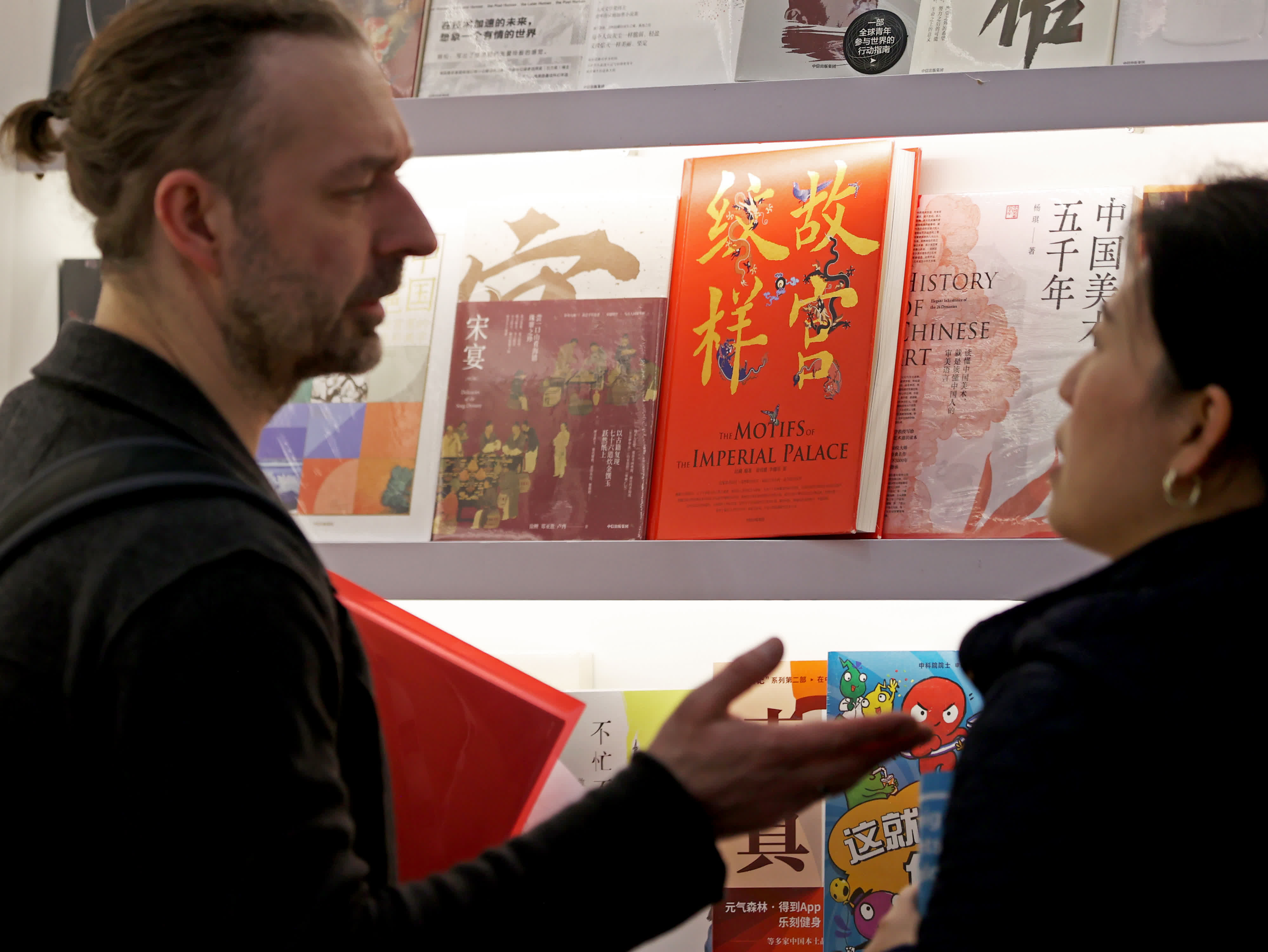 3月12日，一名參展商在英國倫敦書展中國出版單位的聯合展台與工作人員交談。（新華社）