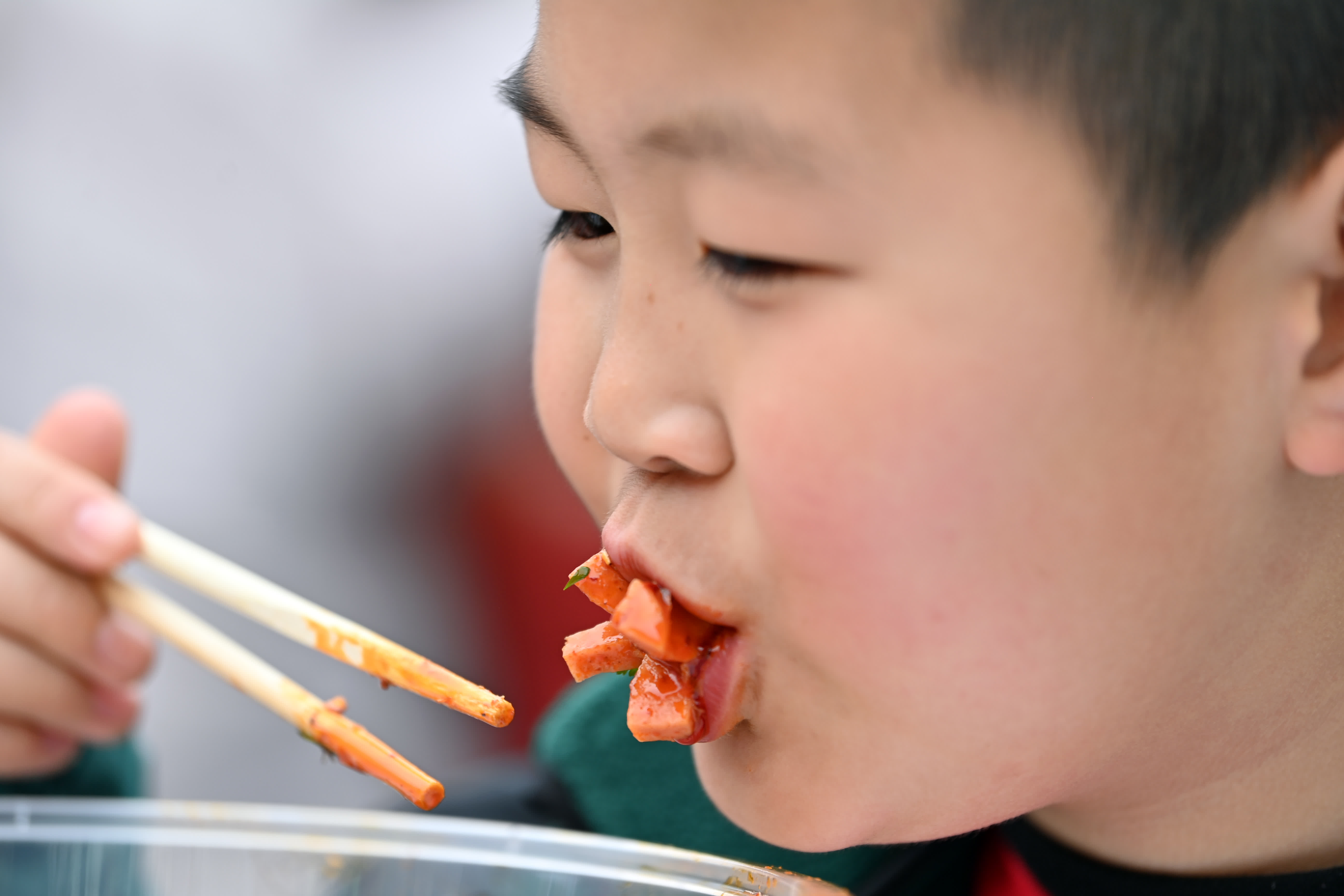 3月16日，來自陝西寶雞的小朋友在甘肅天水古城品嚐麻辣燙。（中新社）