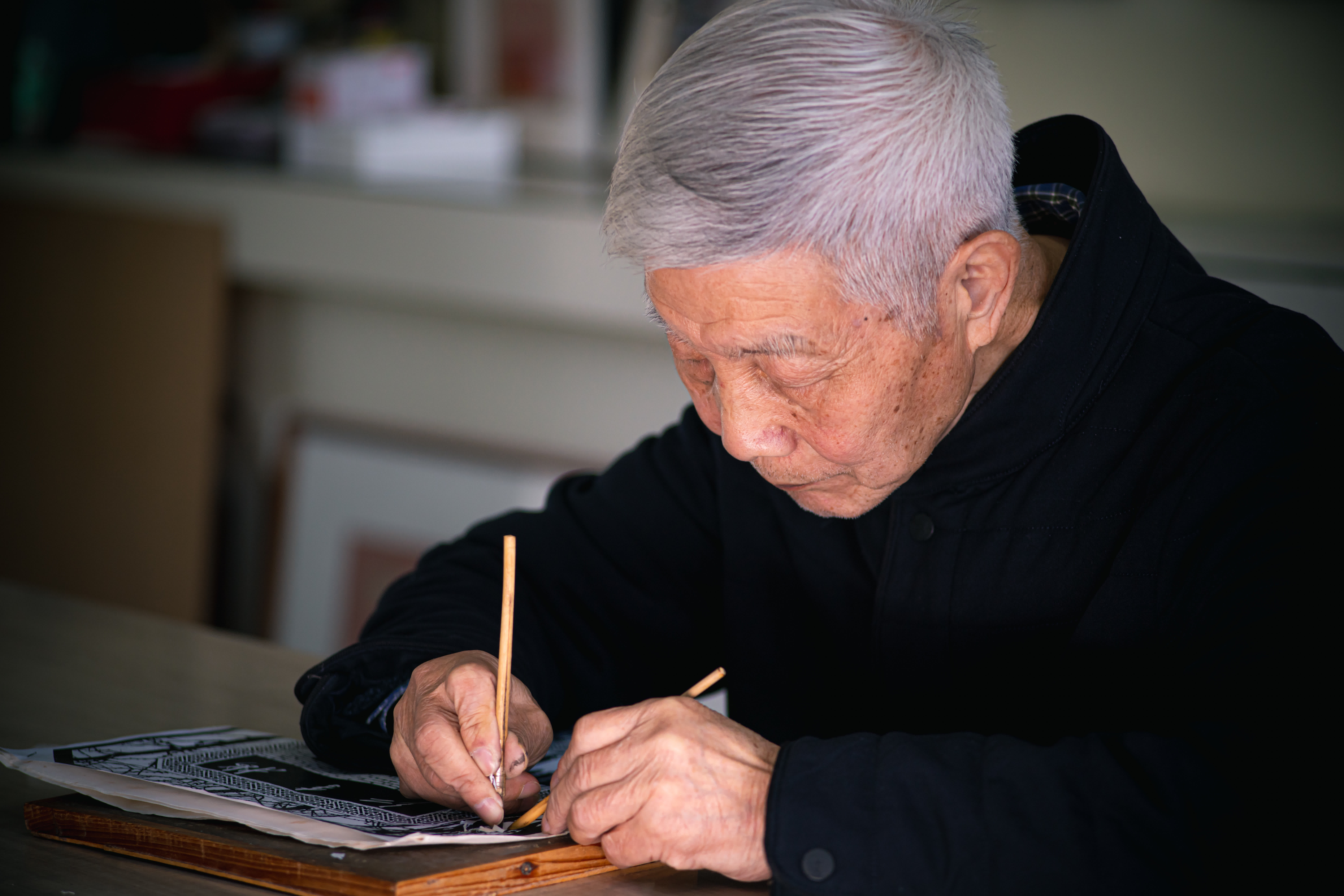 盧發良在工作室內創作一幅細紋刻紙作品（3月12日攝）。（新華社）