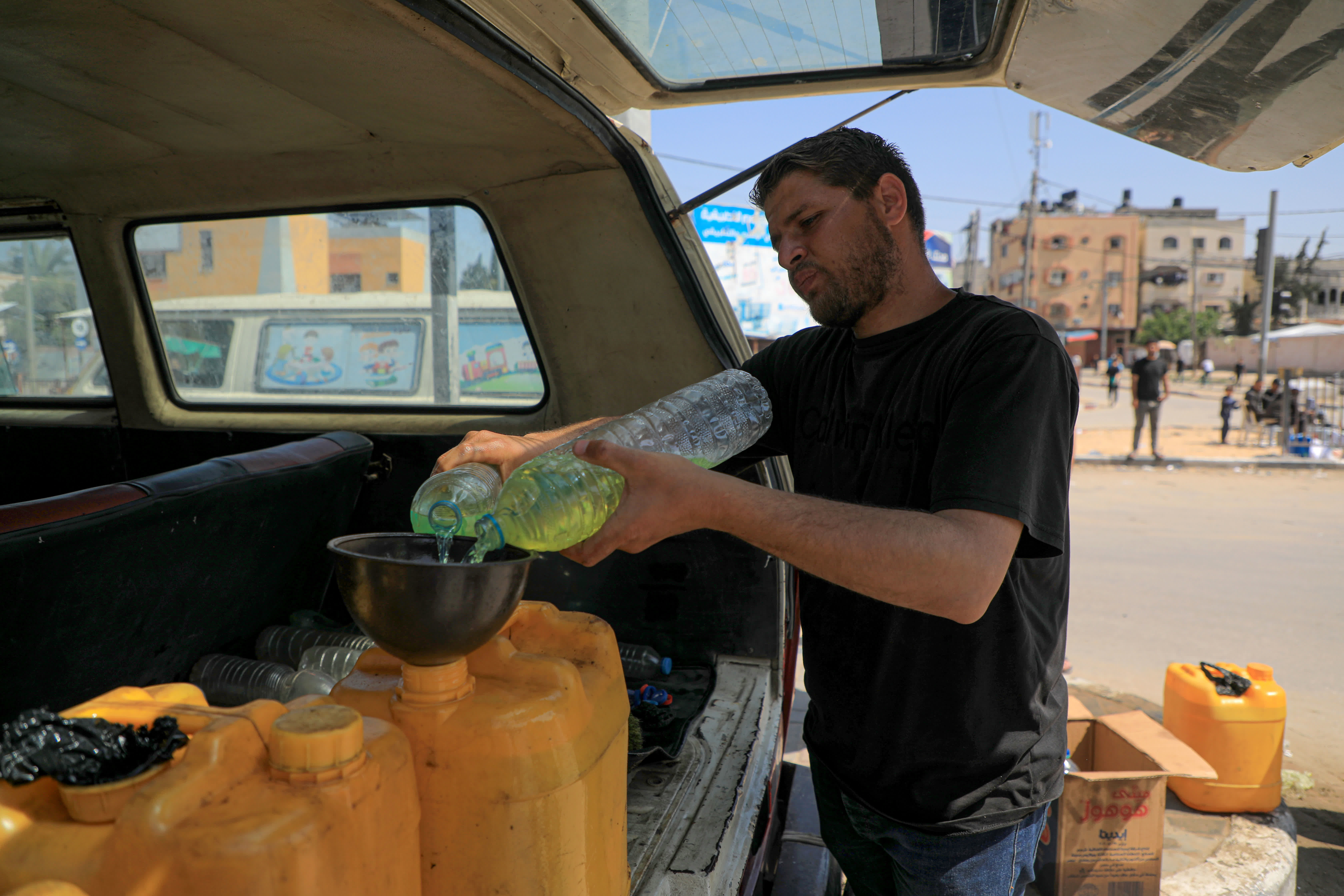 4月16日，在加沙地帶中部城市代爾拜拉赫，巴勒斯坦人正在向油桶裏填充燃料。（新華社）
