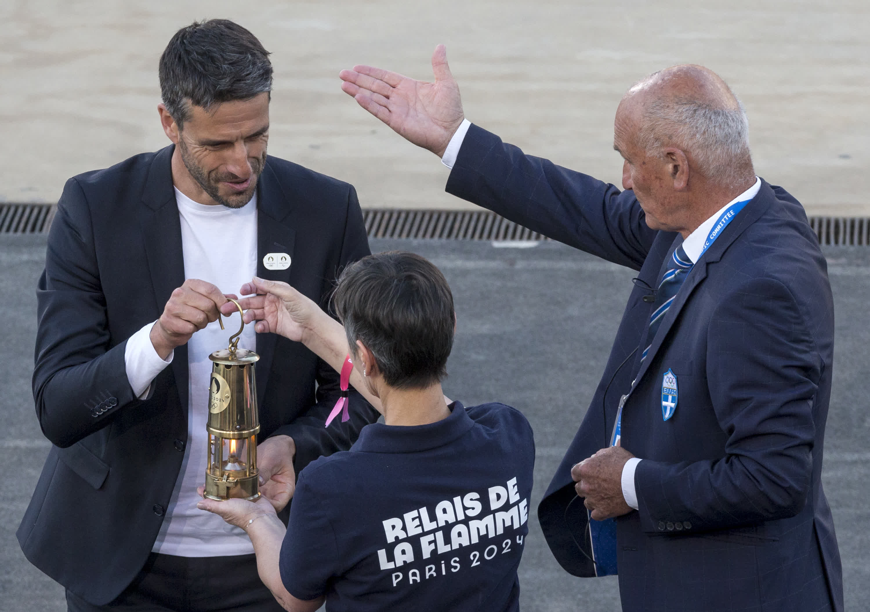 4月26日，巴黎奧組委主席托尼·埃斯坦蓋（左）將巴黎奧運會火種燈交給工作人員。（新華社）