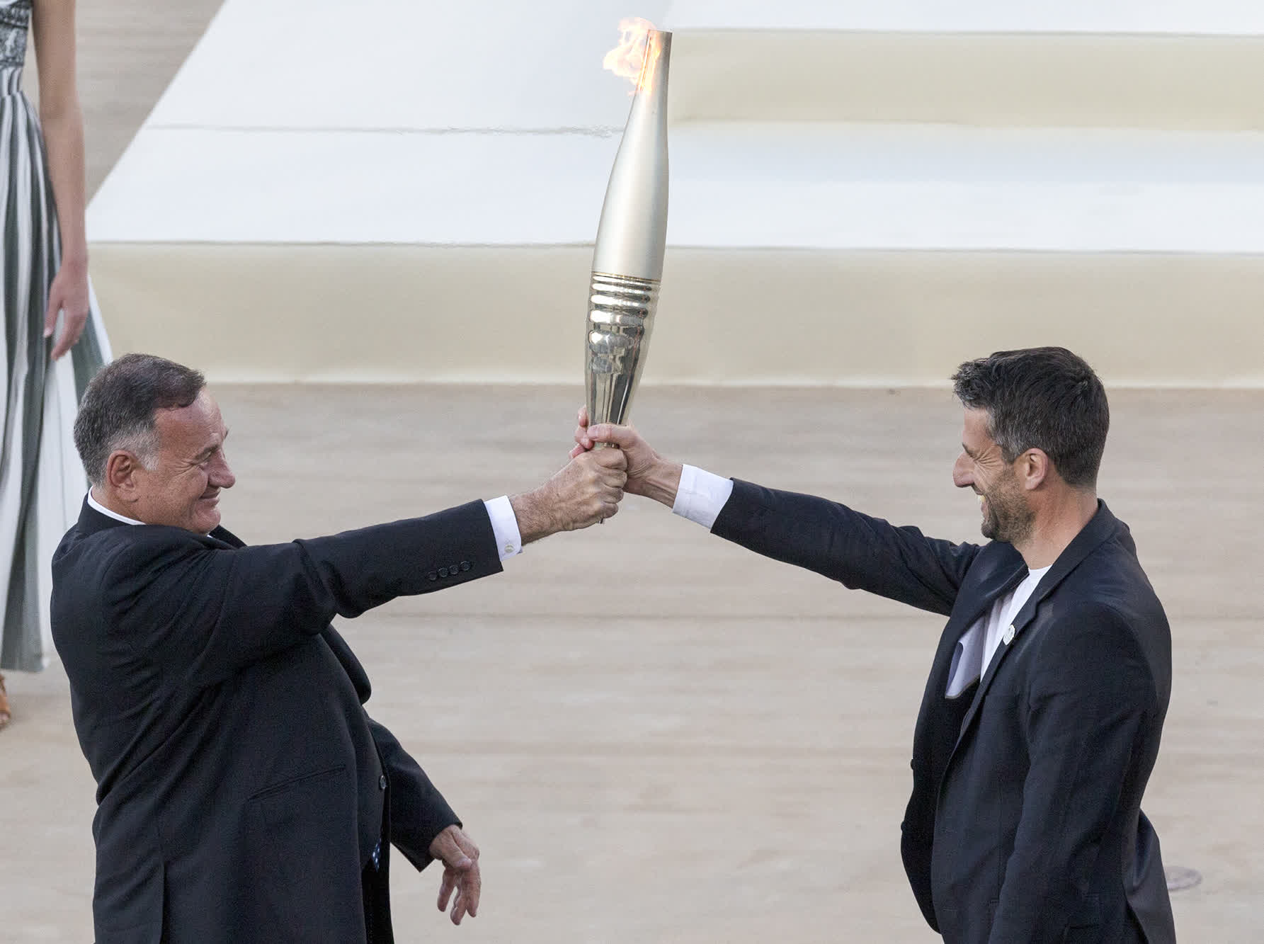4月26日，希臘奧委會主席卡普拉洛斯（左）將火炬交給巴黎奧組委主席托尼·埃斯坦蓋。（新華社）
