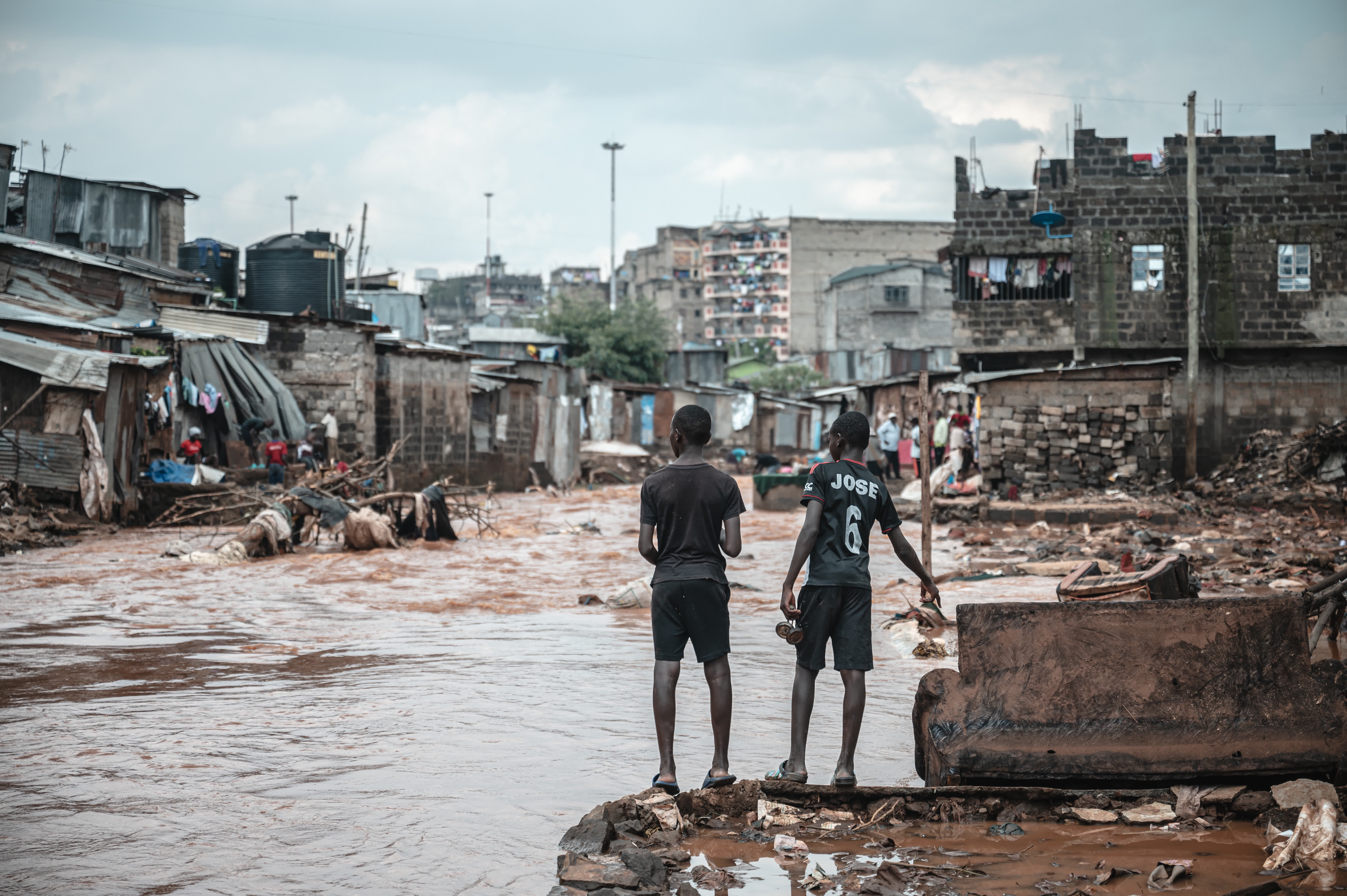 4月30日，在肯尼亞首都內羅畢的馬薩雷貧民區，兩名青少年站在被洪水沖毀的廢墟上。（新華社）