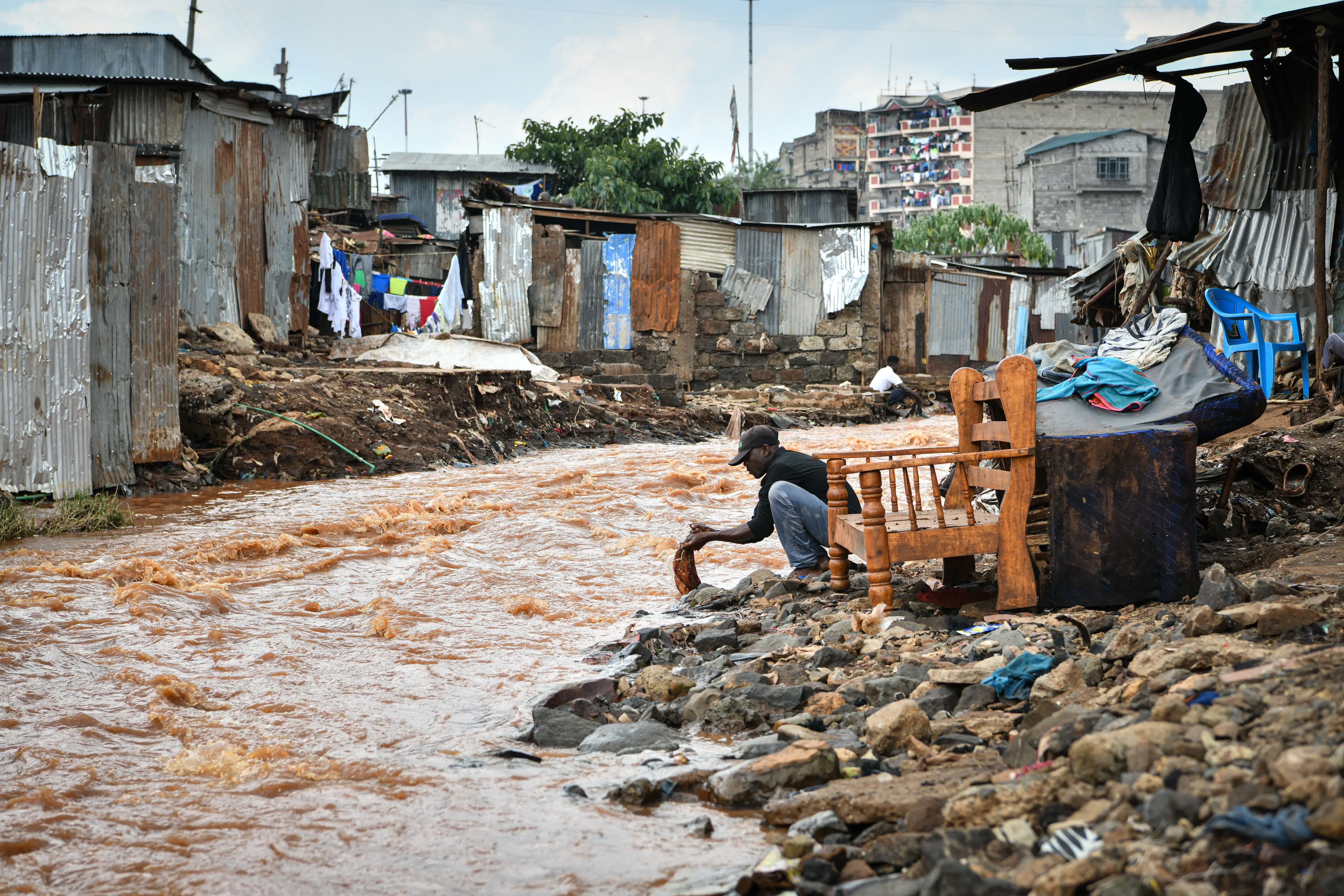 4月30日，在肯尼亞首都內羅畢的馬薩雷貧民區，人們在氾濫的馬薩雷河旁用水。（新華社）
