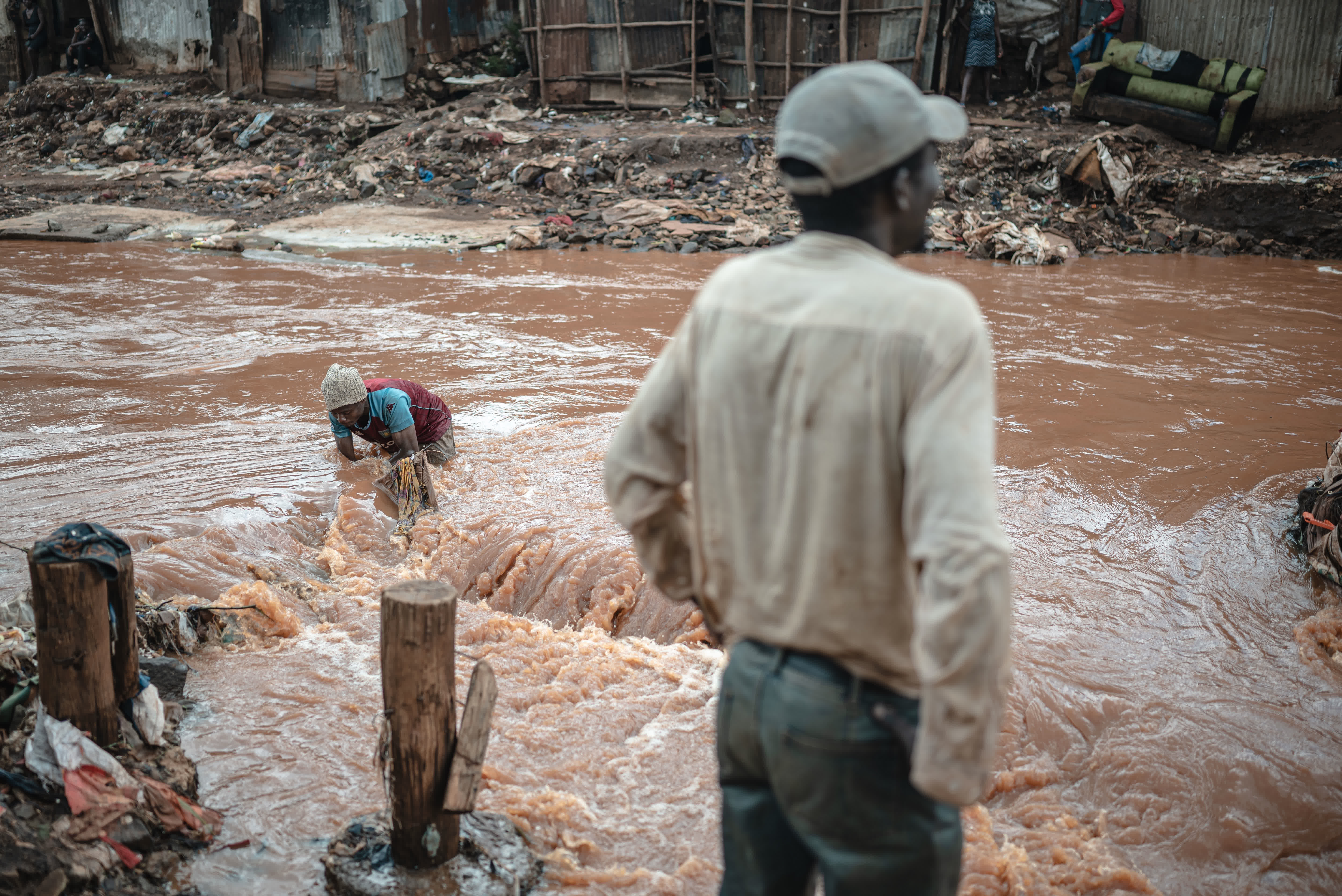 4月30日，在肯尼亞首都內羅畢的馬薩雷貧民區，一名男子在馬薩雷河中撿拾被水沖走的物品。（新華社）