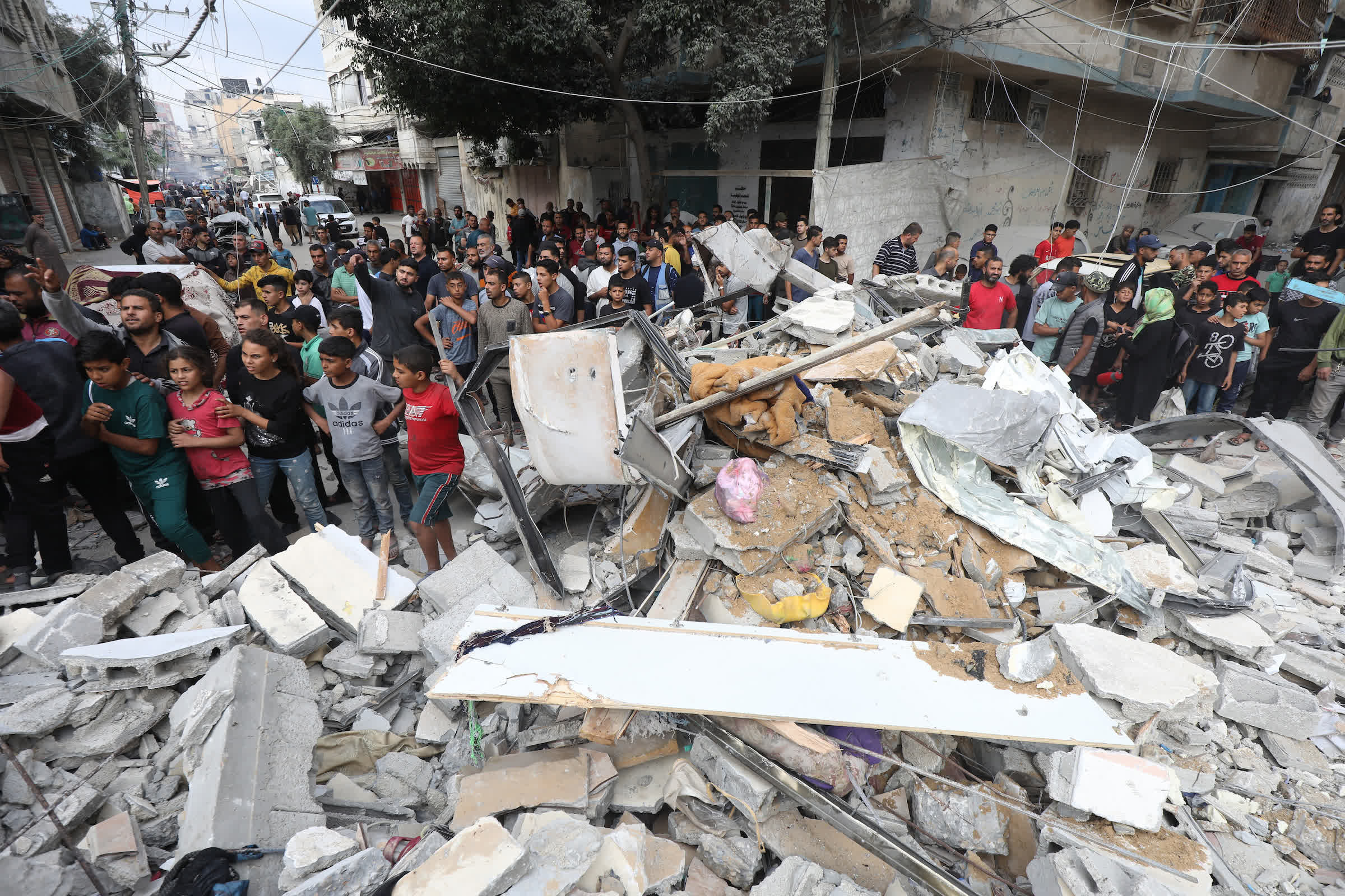 5月14日，在加沙地帶中部努賽賴特難民營，人們查看以軍轟炸後的建築廢墟。新華社發（巴勒斯坦通訊社供圖）