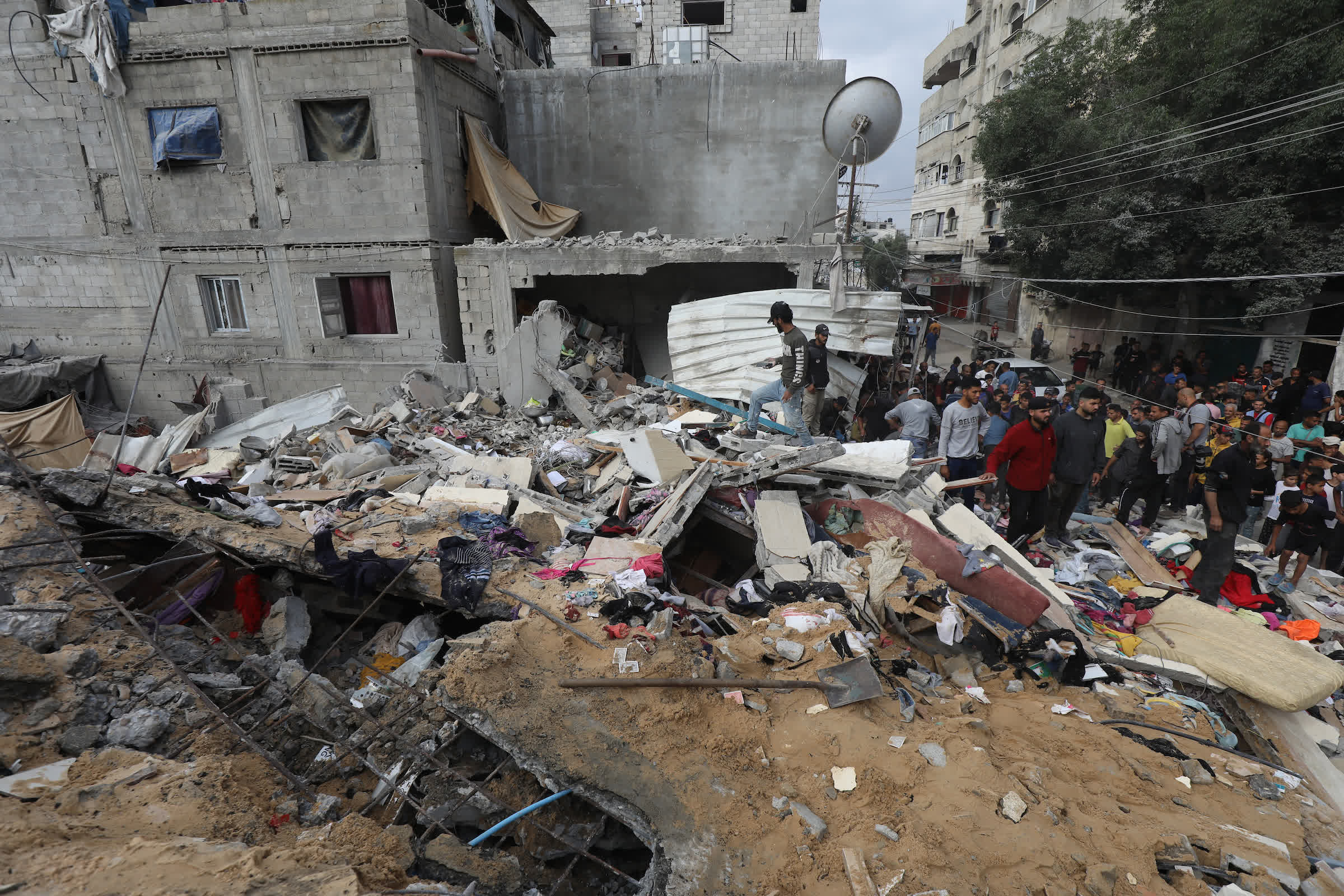 5月14日，在加沙地帶中部努賽賴特難民營，人們查看以軍轟炸後的建築廢墟。新華社發（巴勒斯坦通訊社供圖）