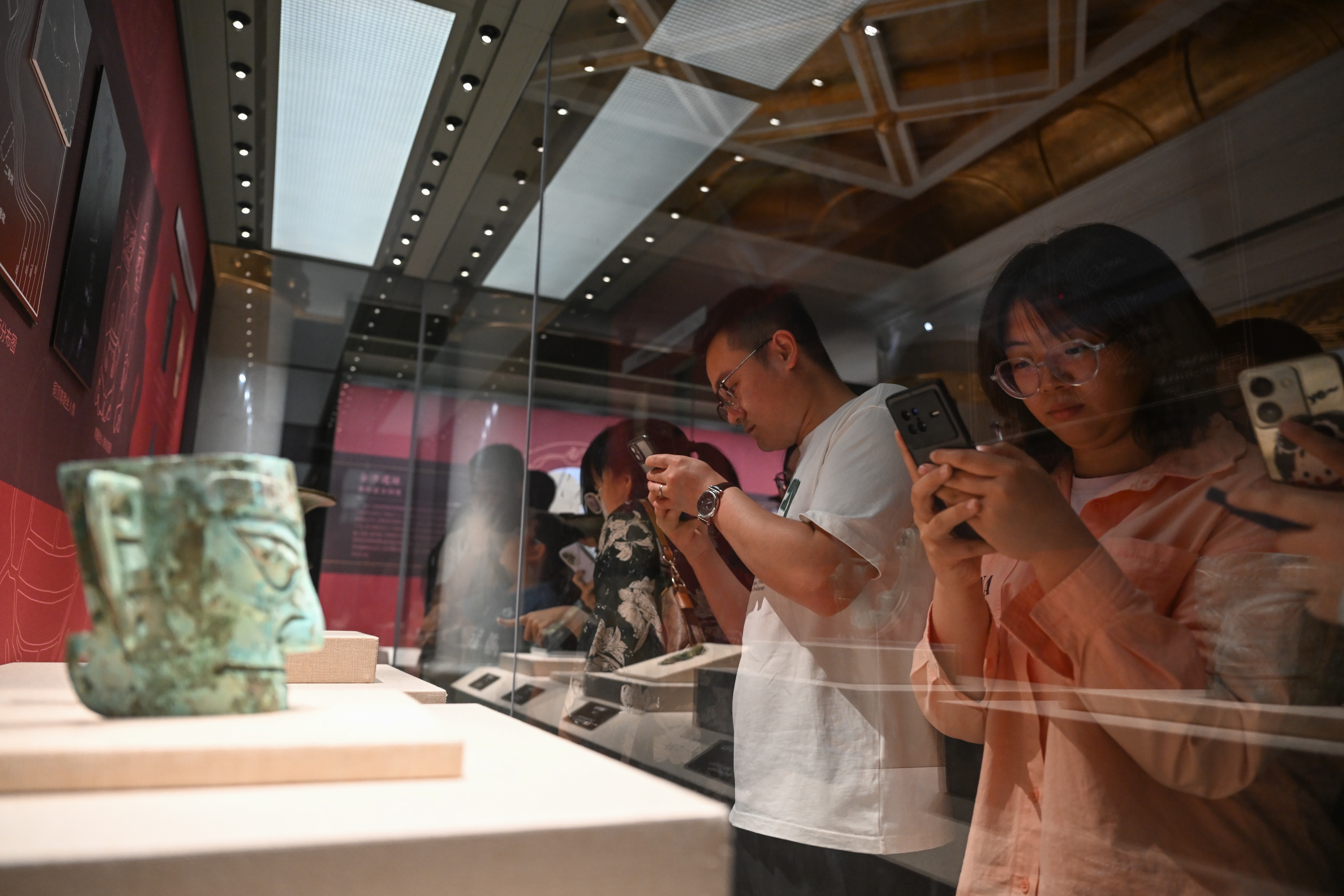 5月18日，參觀者在「問蜀——東周時期的蜀文化展」上觀看、拍攝四川廣漢三星堆遺址出土的銅人面具。（新華社）