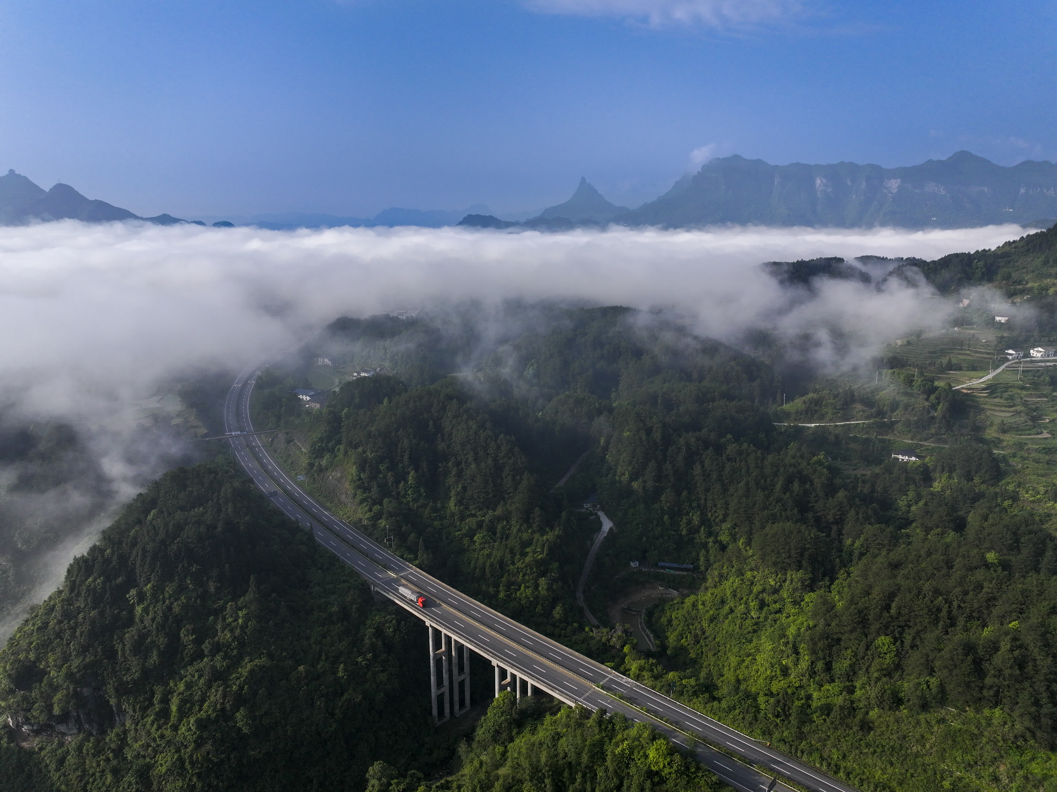 5月23日，重慶市南川區金佛山東麓雲海景觀與山間的高速公路交織（無人機照片）。（新華社）