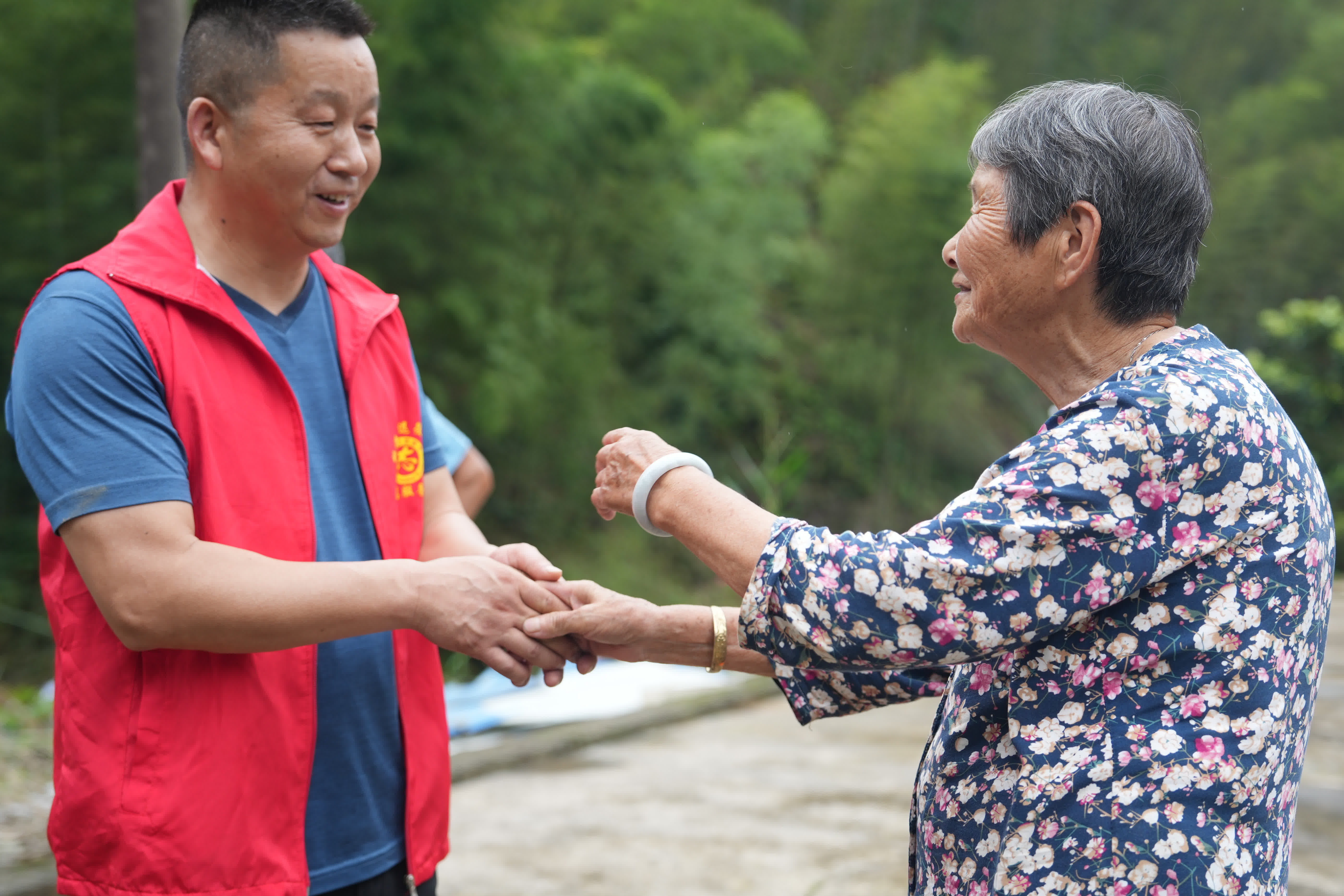 6月25日，受災村民（右）對前來(lái)運送物資的志願者表示感謝。（新華社）