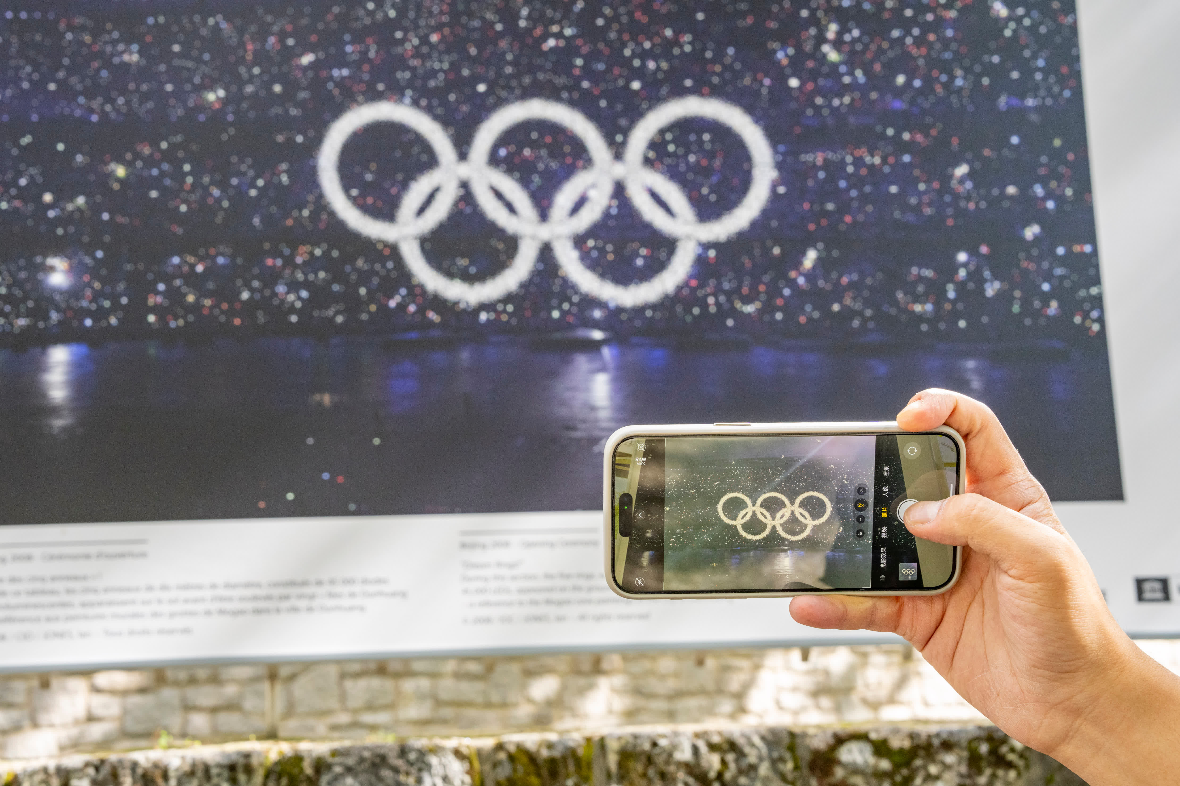 7月6日，一名參觀者用手機拍攝聯合國教科文組織展出的北京奧運會開幕式照片。（新華社）