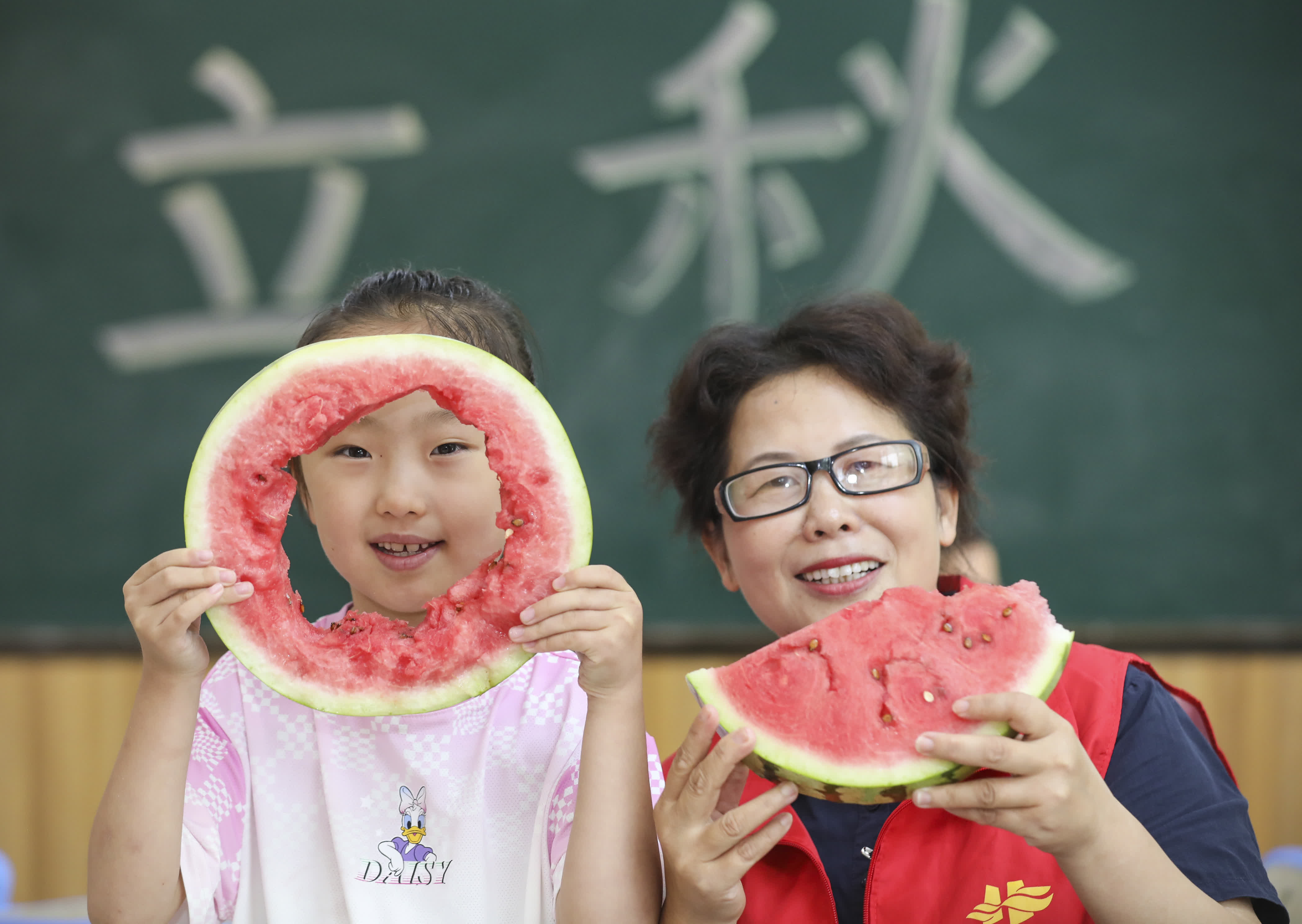 8月7日，江蘇省淮安市清江浦區西安路社區志願者和小朋友一起「啃秋」吃西瓜。（新華社）