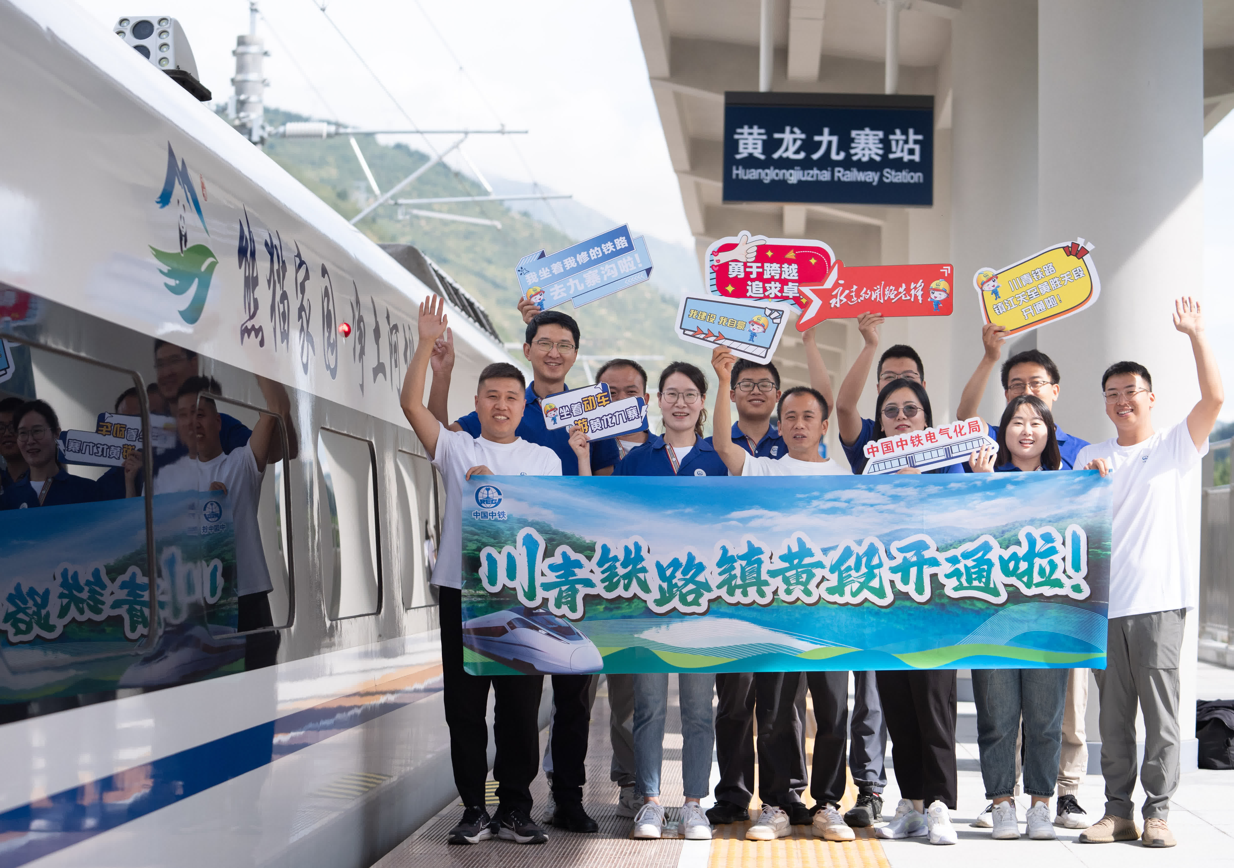 參與川青鐵路鎮江關至黃勝關段修建的中國中鐵電氣化局員工在黃龍九寨站首發列車前留影。（新華社）