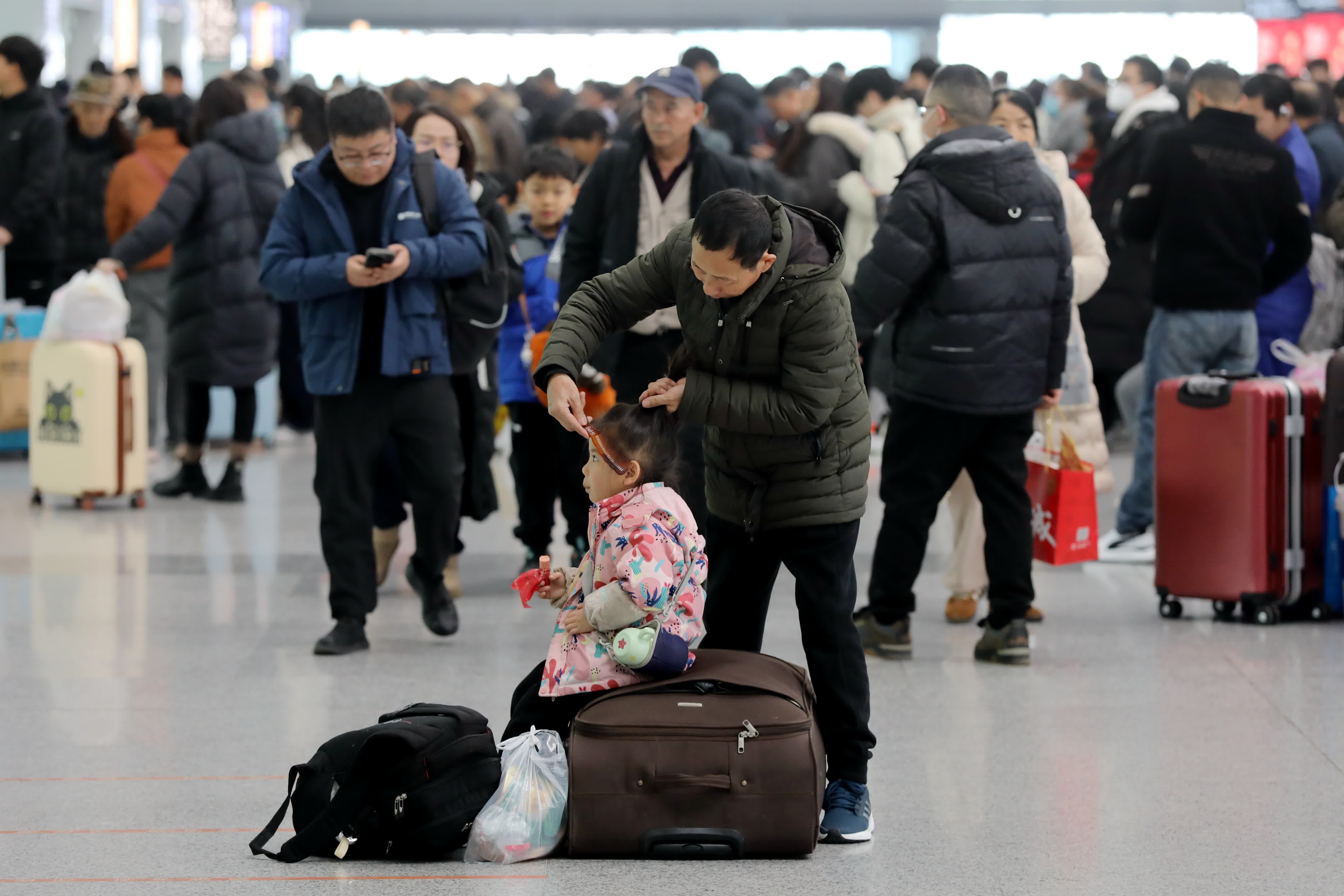 1月14日，2025年春運(yùn)正式啟動(dòng)。圖為旅客在西安北站候車大廳內(nèi)為孫女梳頭。 中新社
  