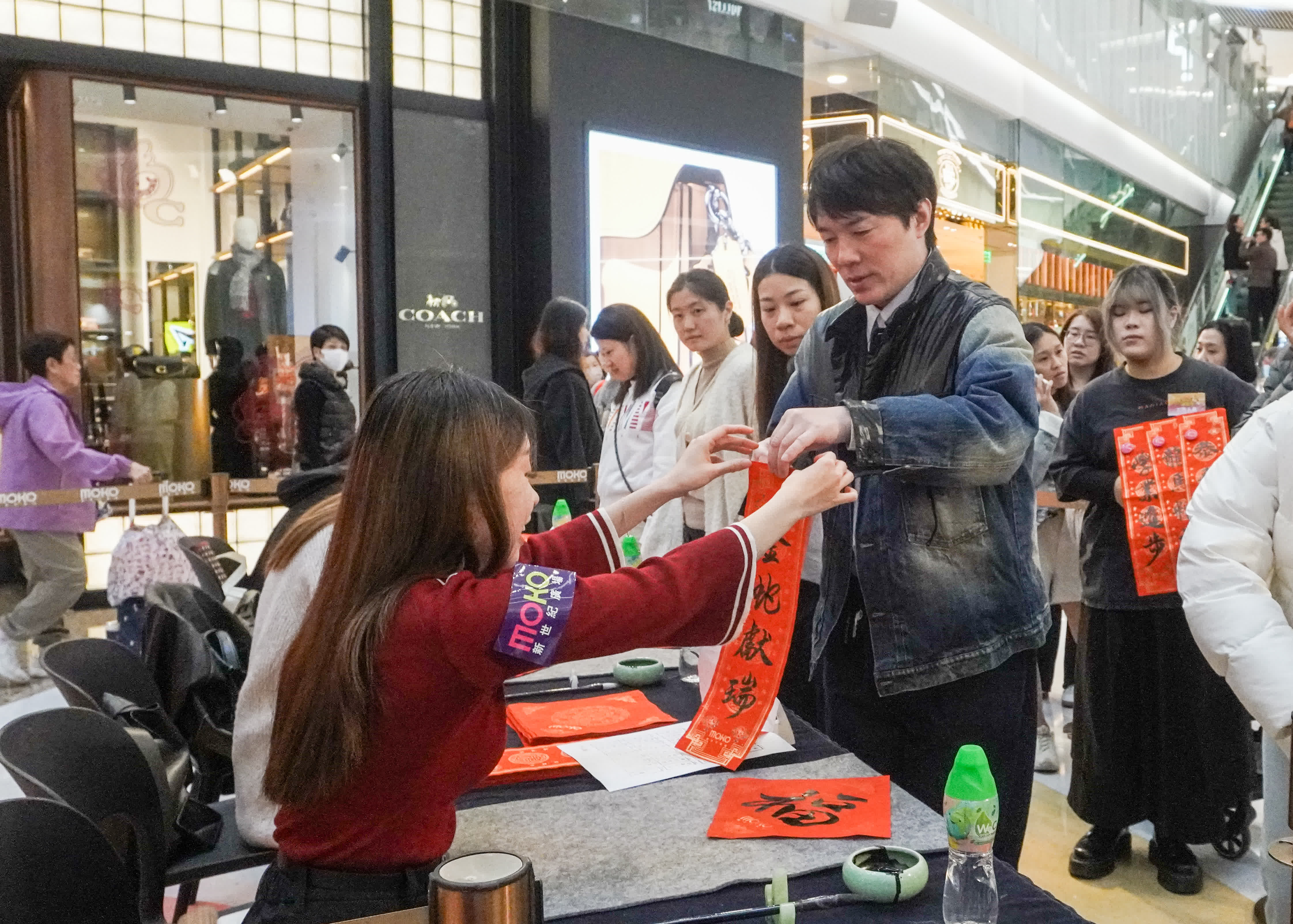 圖為旺角東一間商場，年貨鋪位火爆，人流眾多，商場亦派發揮春吸引市民。（香港中通社）