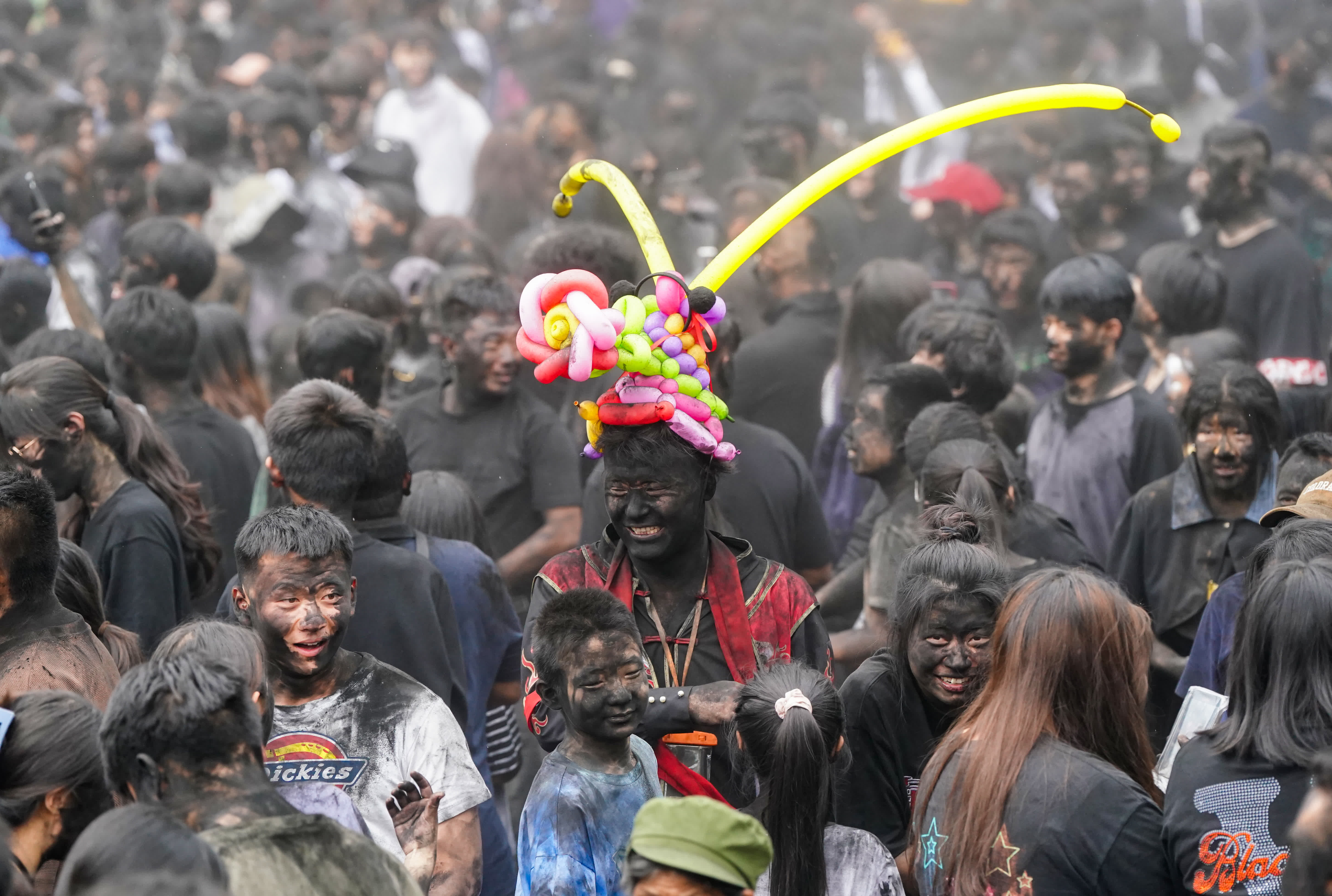 5月2日，頭戴氣球帽的遊客在墨江參加「抹黑臉」狂歡。（新華社）