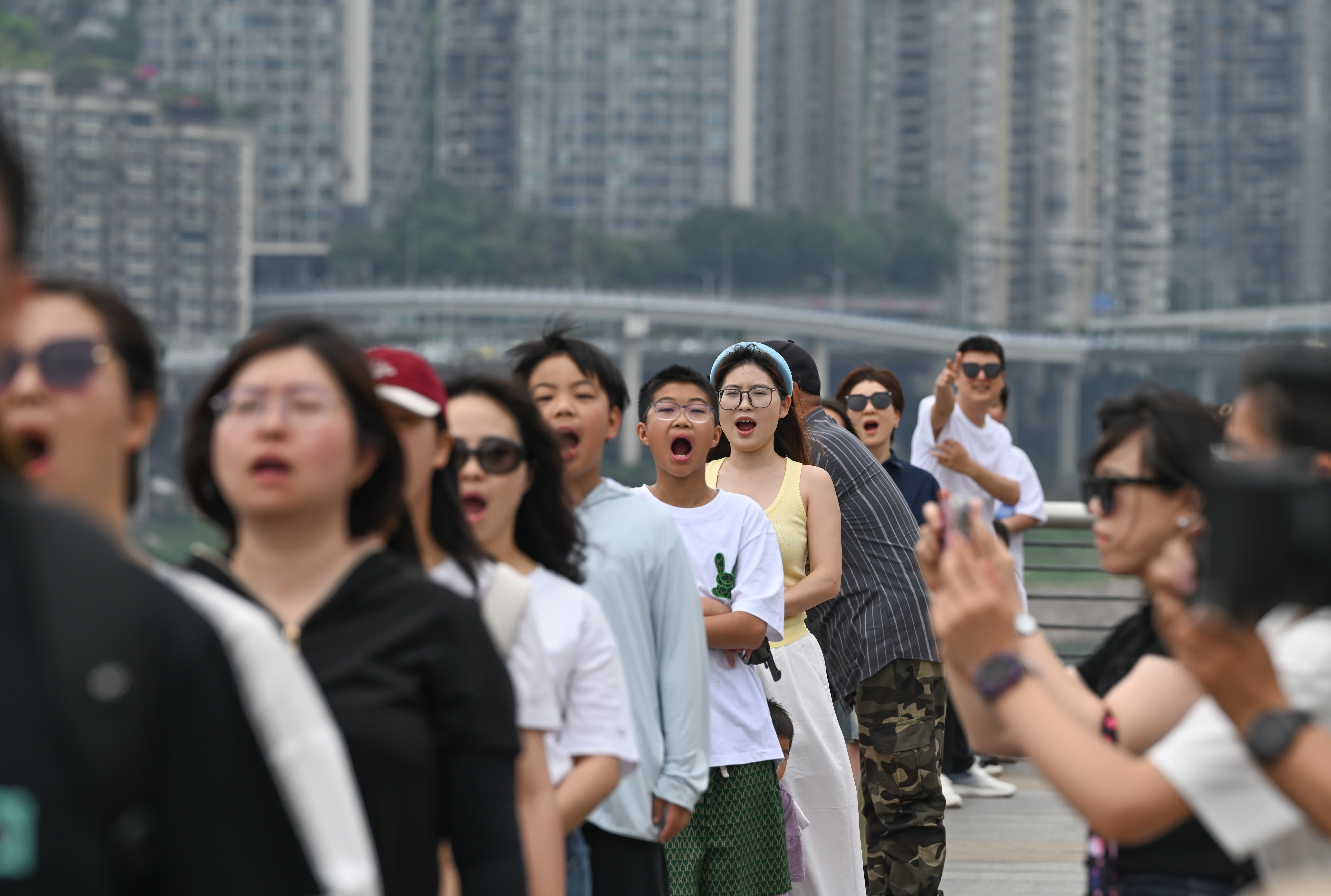 5月4日,在重慶市北濱路,來自各地的遊客擺出「吃」輕軌的姿勢拍照。(新華社) 5月4日,在重慶市北濱路,來自各地的遊客擺出「吃」輕軌的姿勢拍照。(新華社)