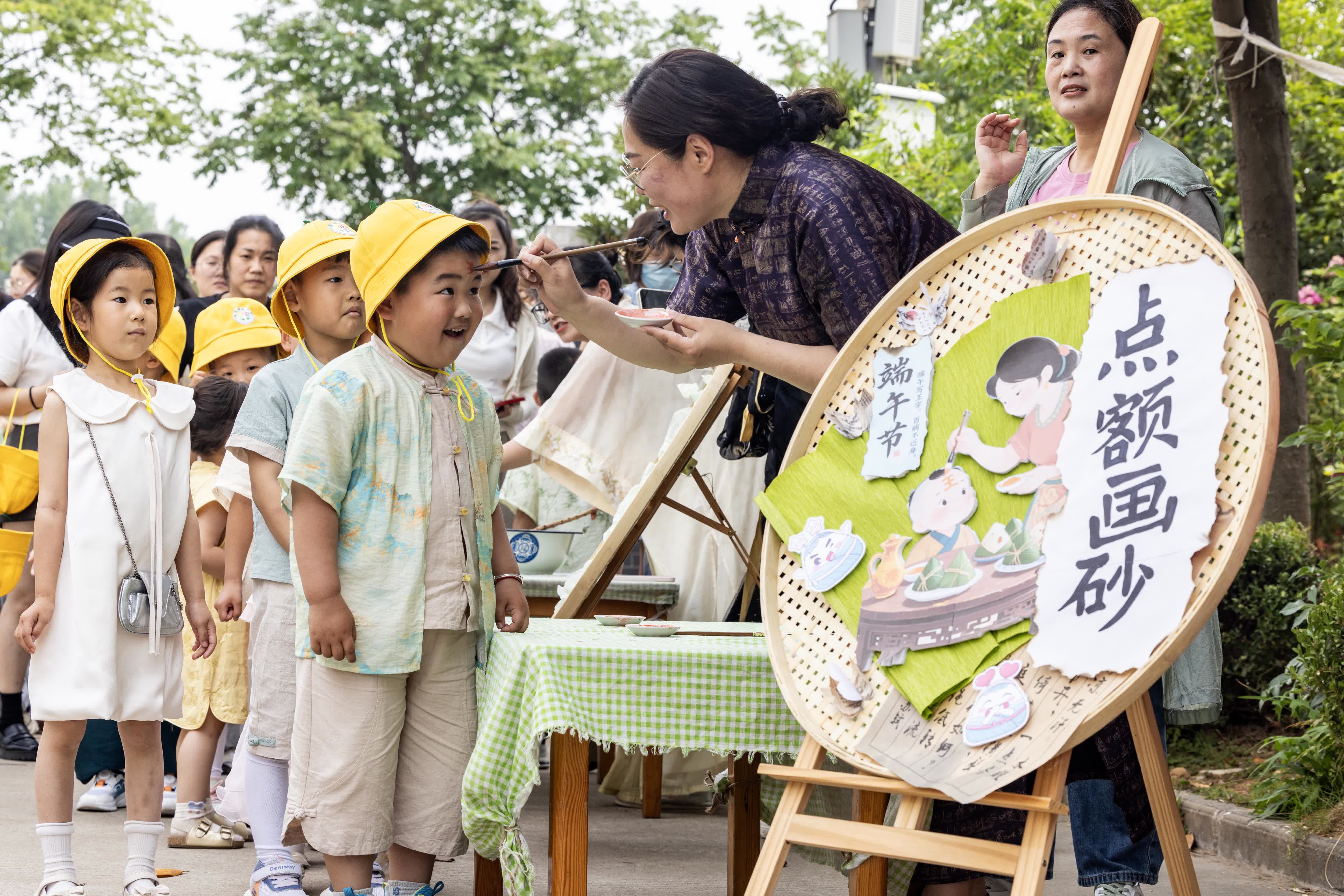 5月30日，老師在江蘇省泰州市海陵區秋雪湖幼兒園給小朋友額頭上點硃砂。（新華社）
