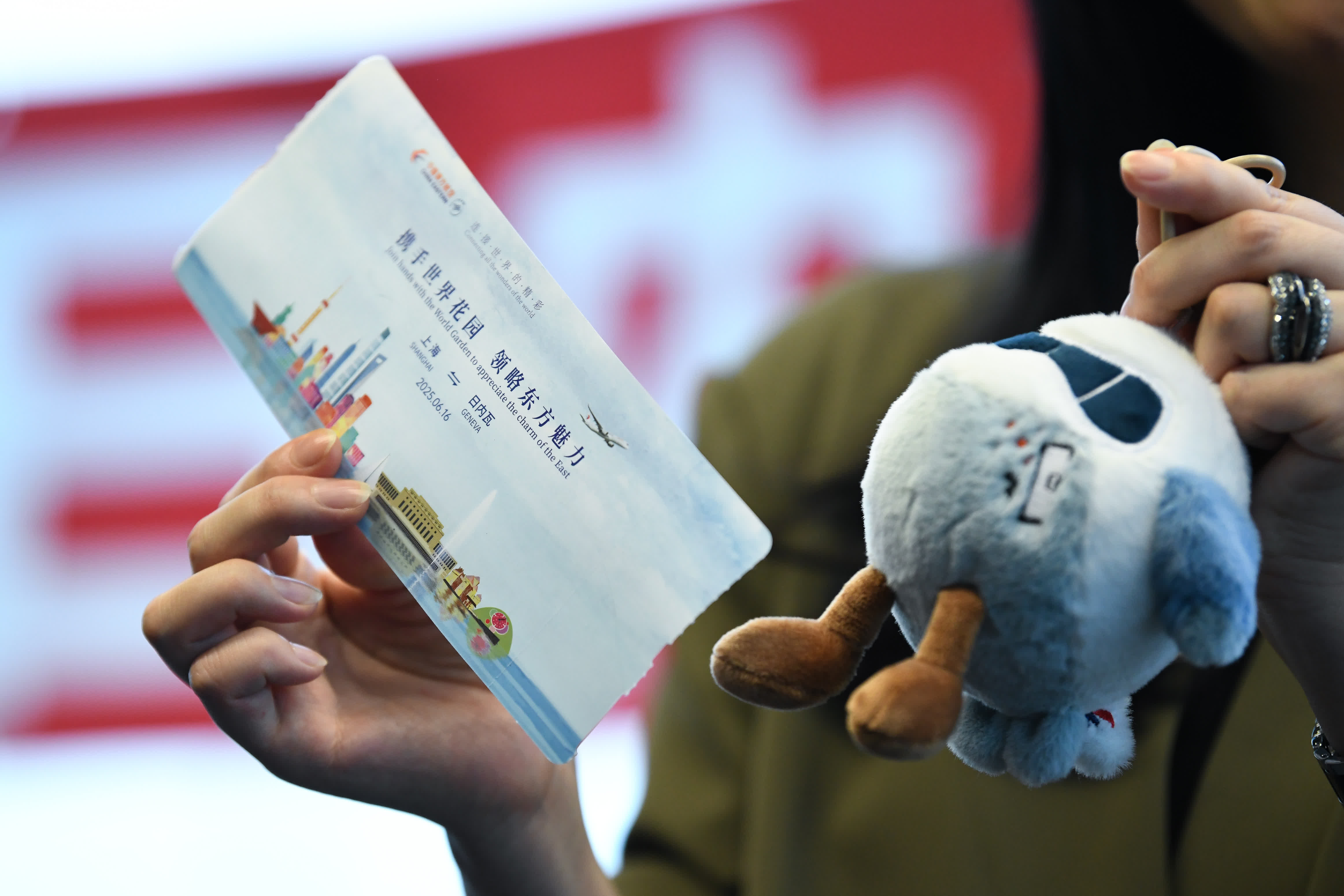 6月16日，在瑞士日內瓦國際機場，MU217航班乘客展示為紀念上海至日內瓦首條直飛航線開通製作的登機牌和紀念品。（新華社）