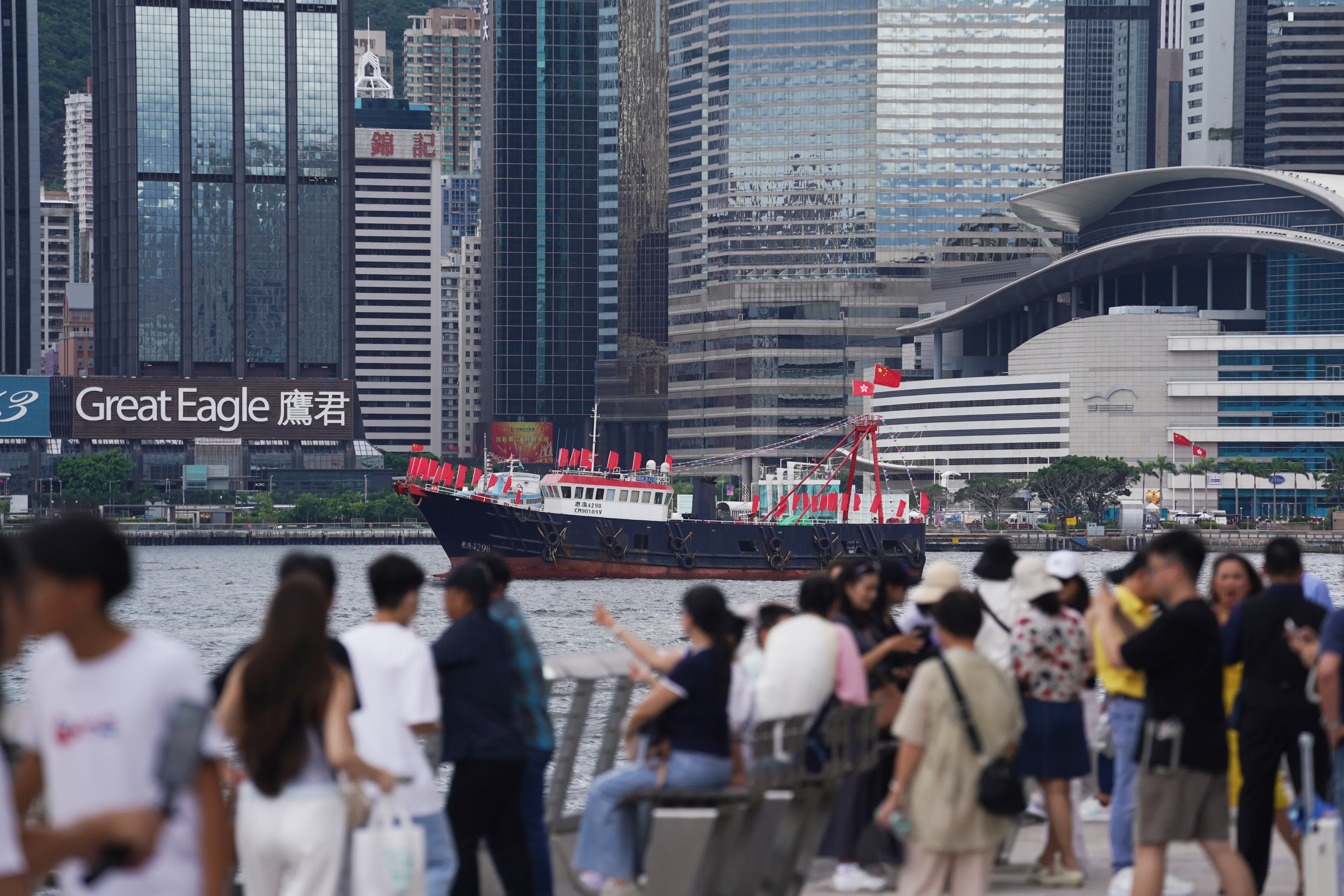 7月1日，市民在香港尖沙咀海濱拍攝巡遊的漁船。（新華社）
