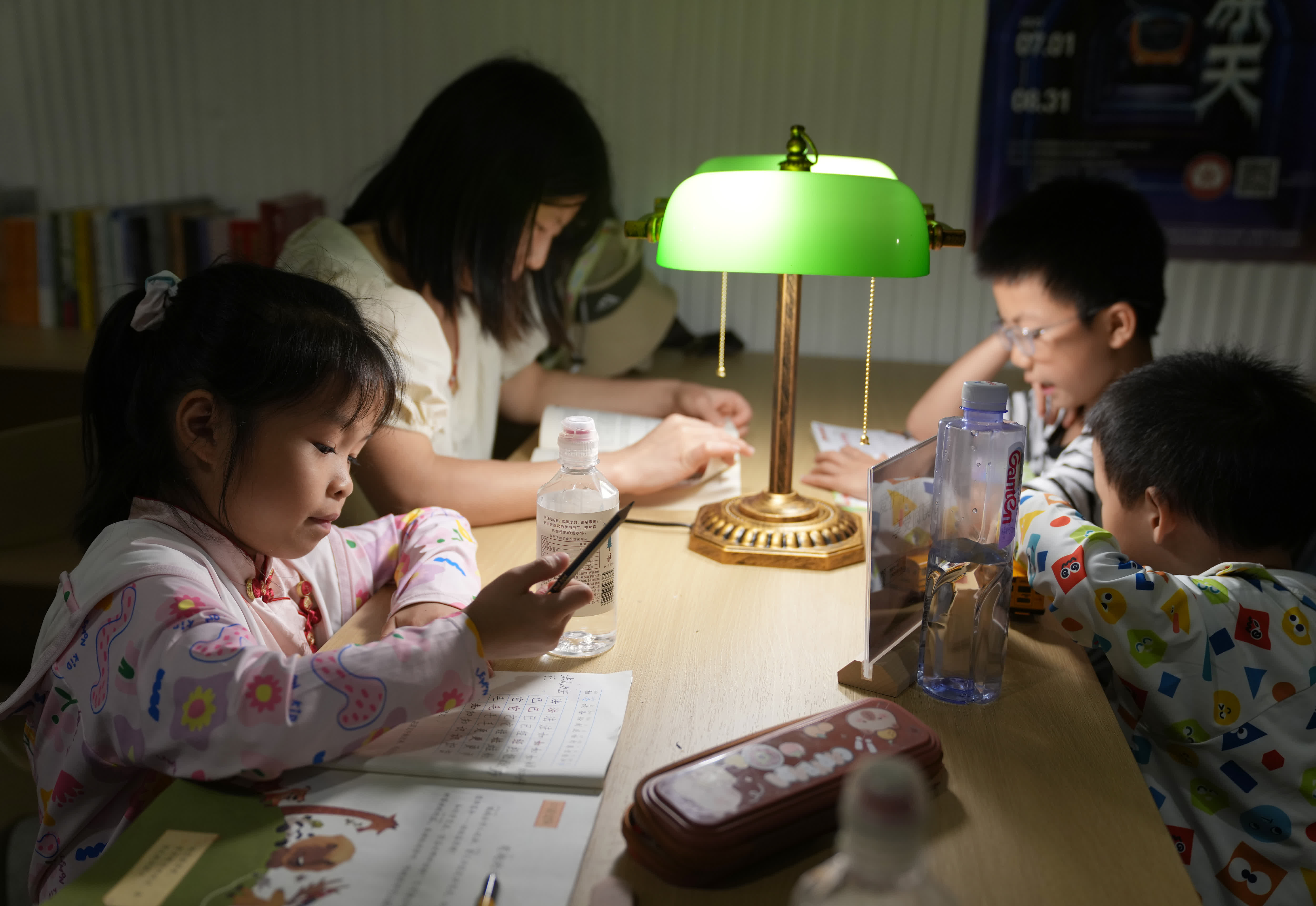 7月1日，一名小朋友（前左）在杭州四牌樓納涼點的共享書屋內寫作業。（新華社）