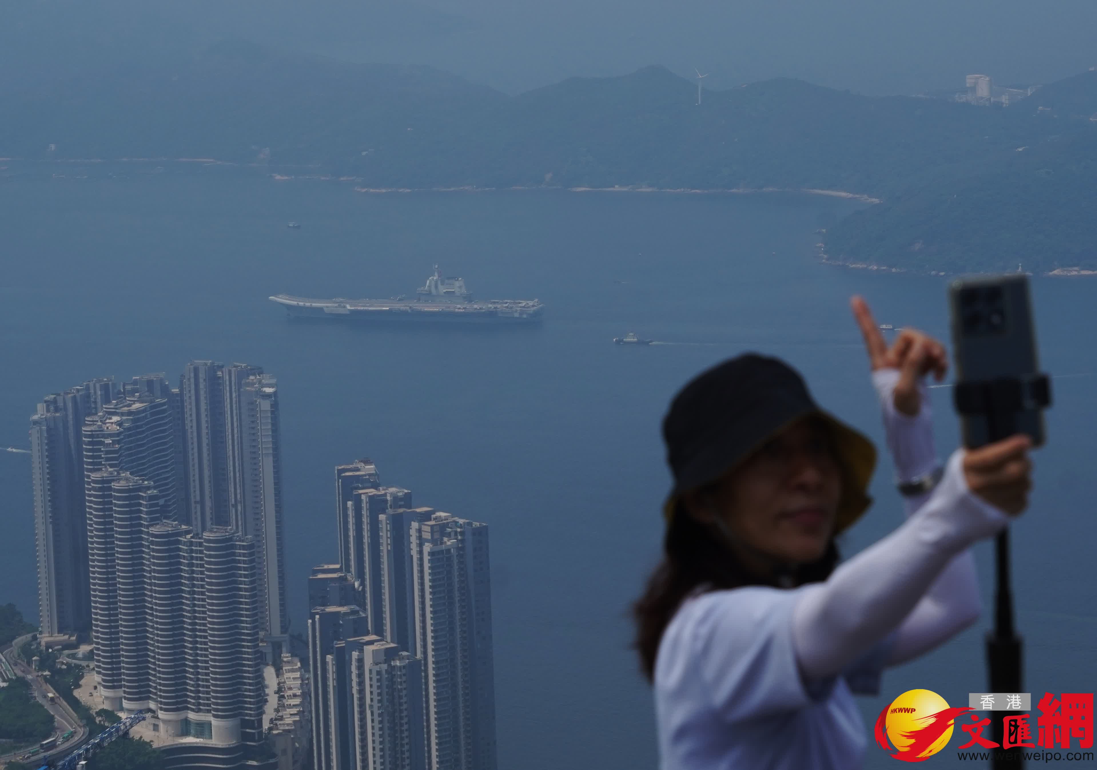 有人舉起手機與艦隊遙遙「自拍」,希望能把這個歷史性畫面鐫刻在照片中。 (香港文匯報記者曾興偉 攝) 有人舉起手機與艦隊遙遙「自拍」,希望能把這個歷史性畫面鐫刻在照片中。 (香港文匯報記者曾興偉 攝)