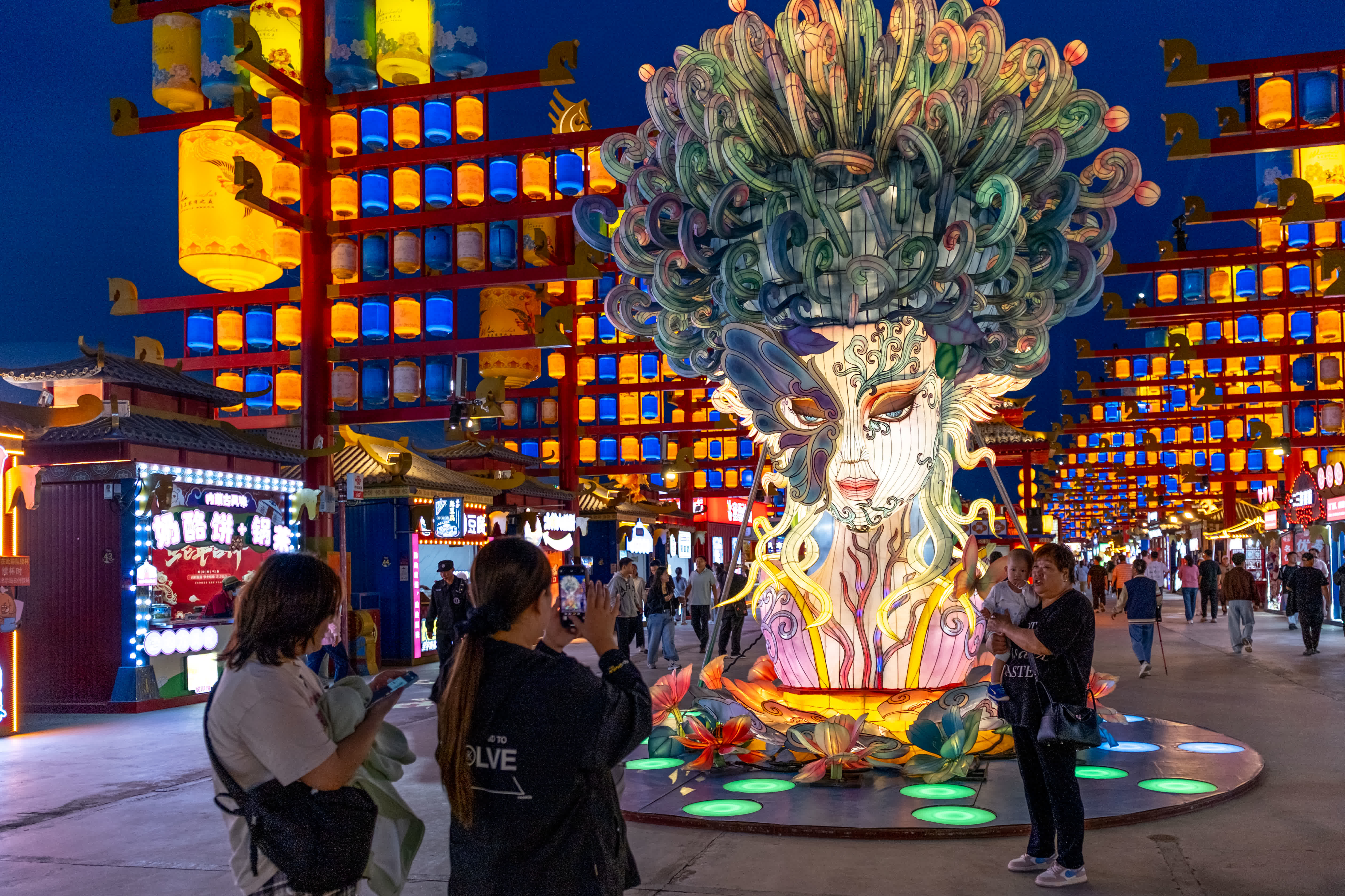 9月4日，在內蒙古烏蘭察布市「烏蘭察布之夜」特色街區，遊客們在花燈前留影。（新華社）