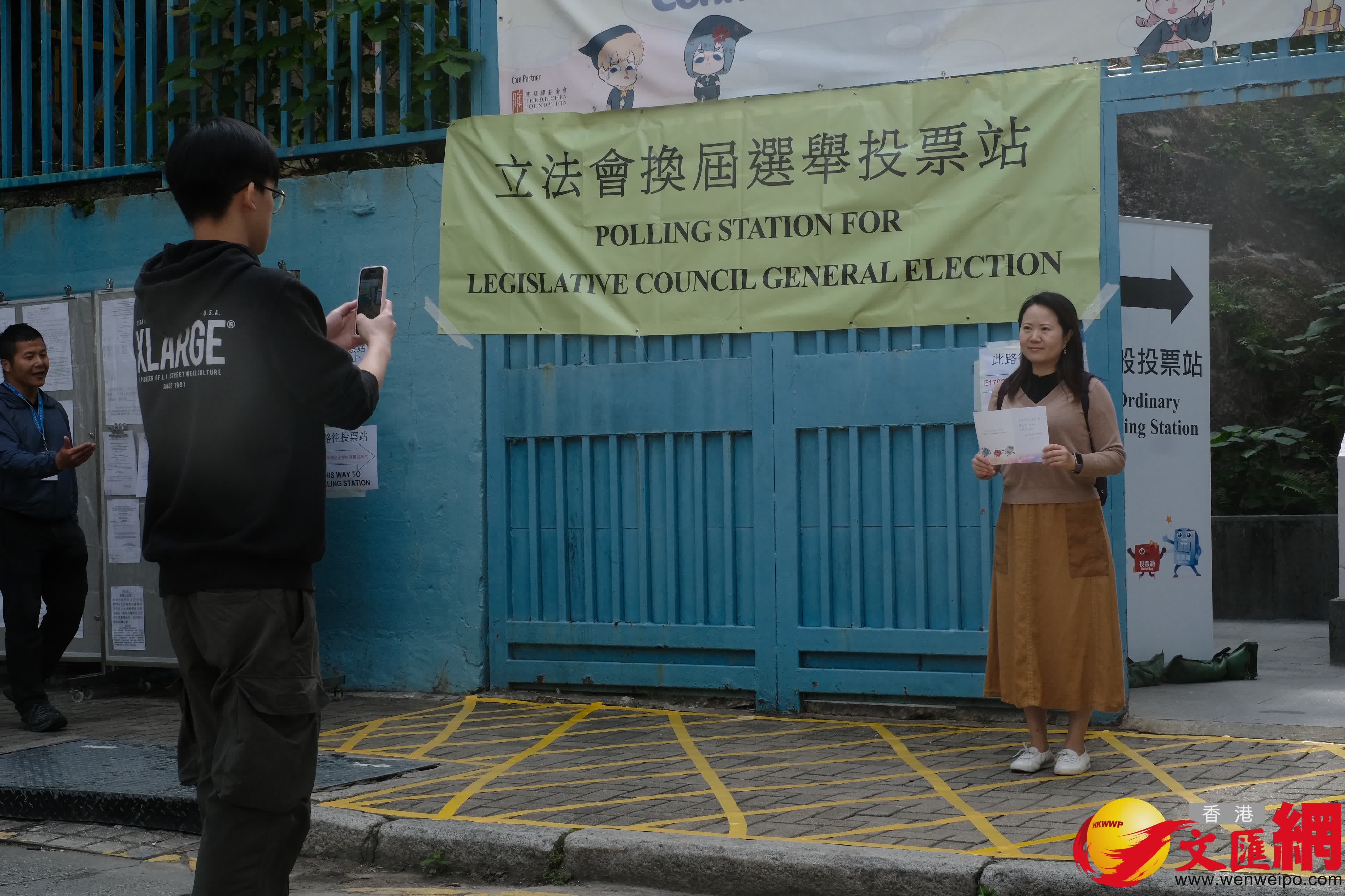 油麻地街坊會學校專屬票站運作順暢，有市民投完票後於門外打卡拍照留念。（香港文匯報記者涂穴攝）