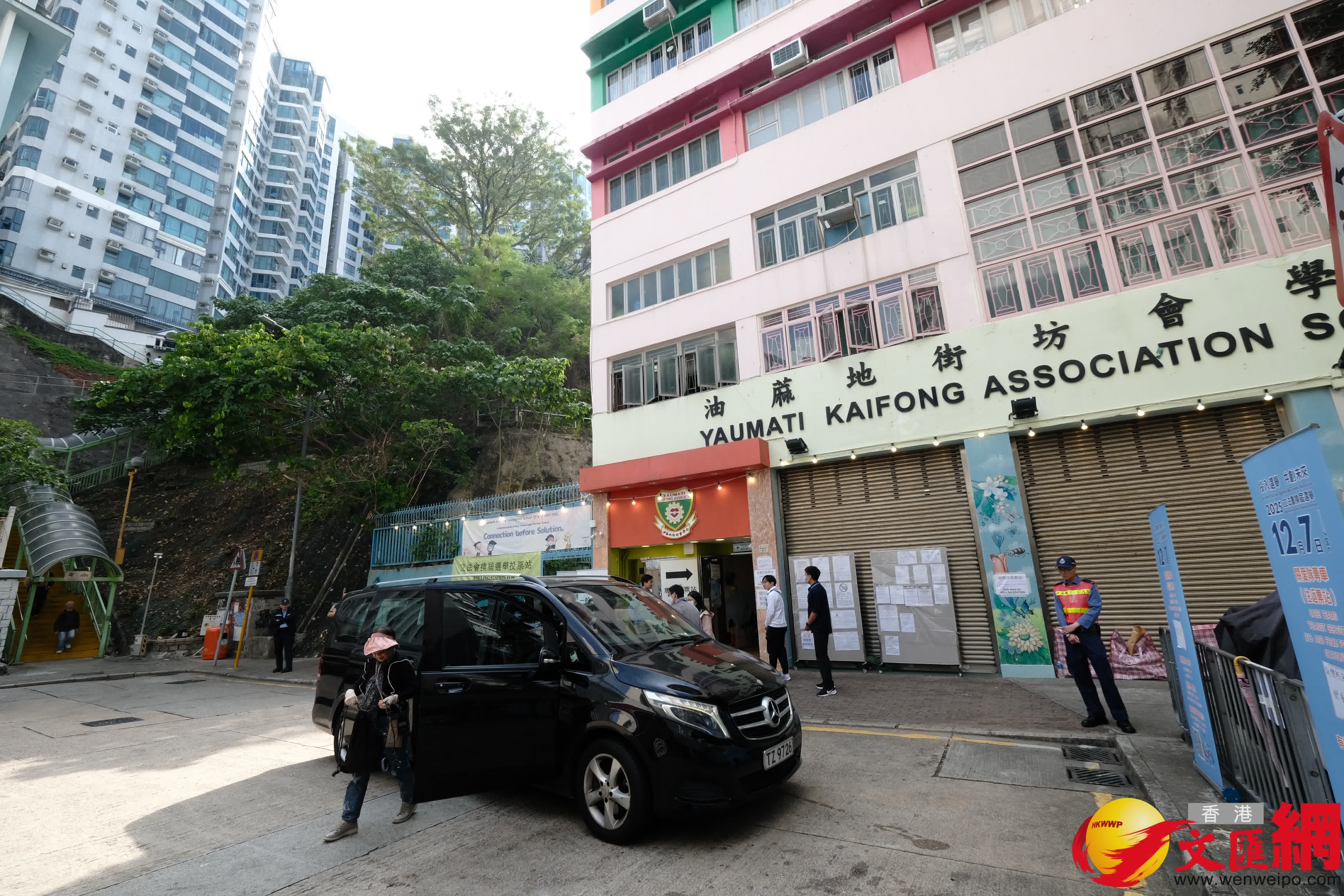 油麻地街坊會學校專屬票站運作順暢，有市民投完票後於門外打卡拍照留念。（香港文匯報記者涂穴攝）