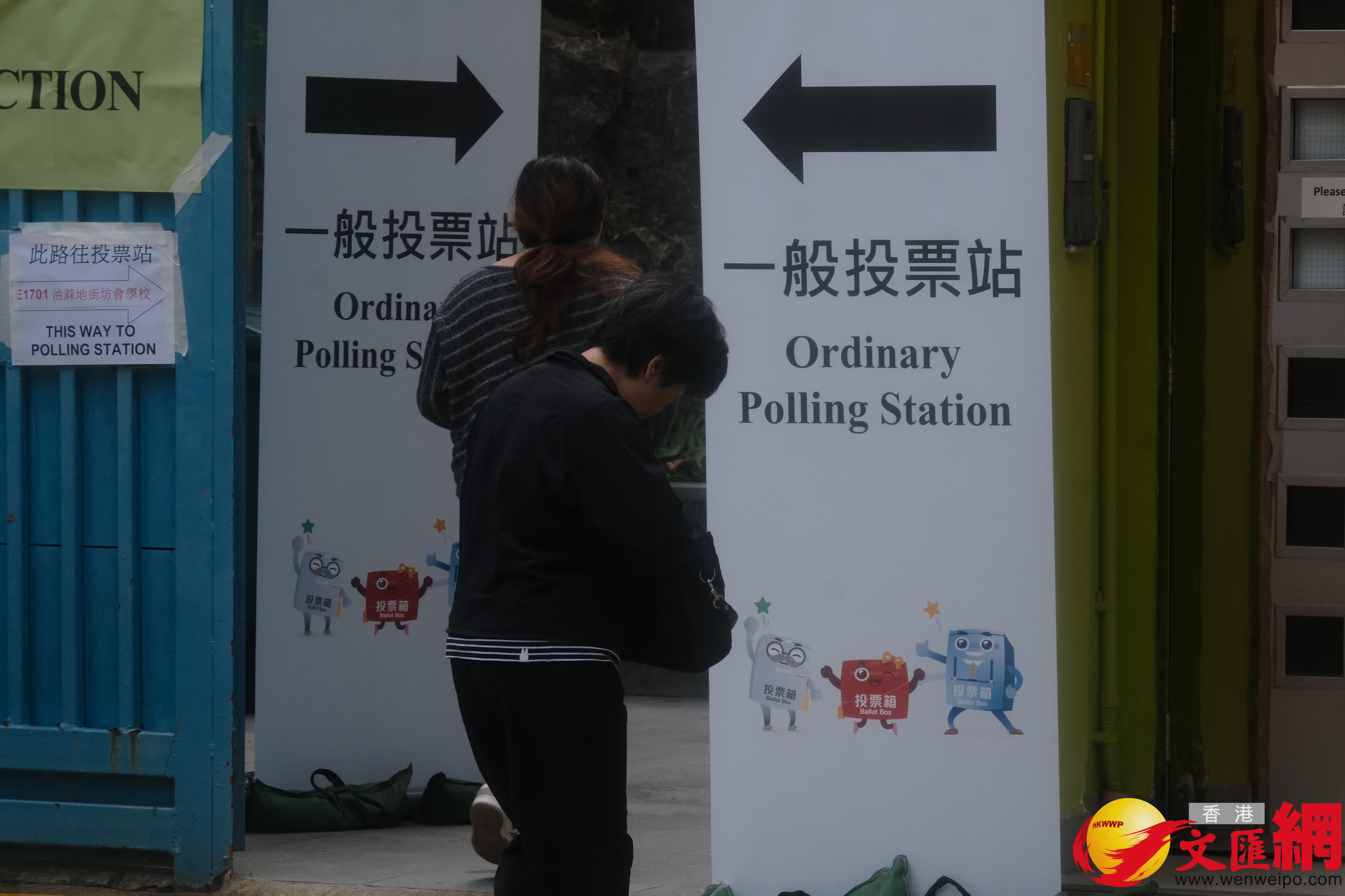 油麻地街坊會學校專屬票站運作順暢，有市民投完票後於門外打卡拍照留念。（香港文匯報記者涂穴攝）