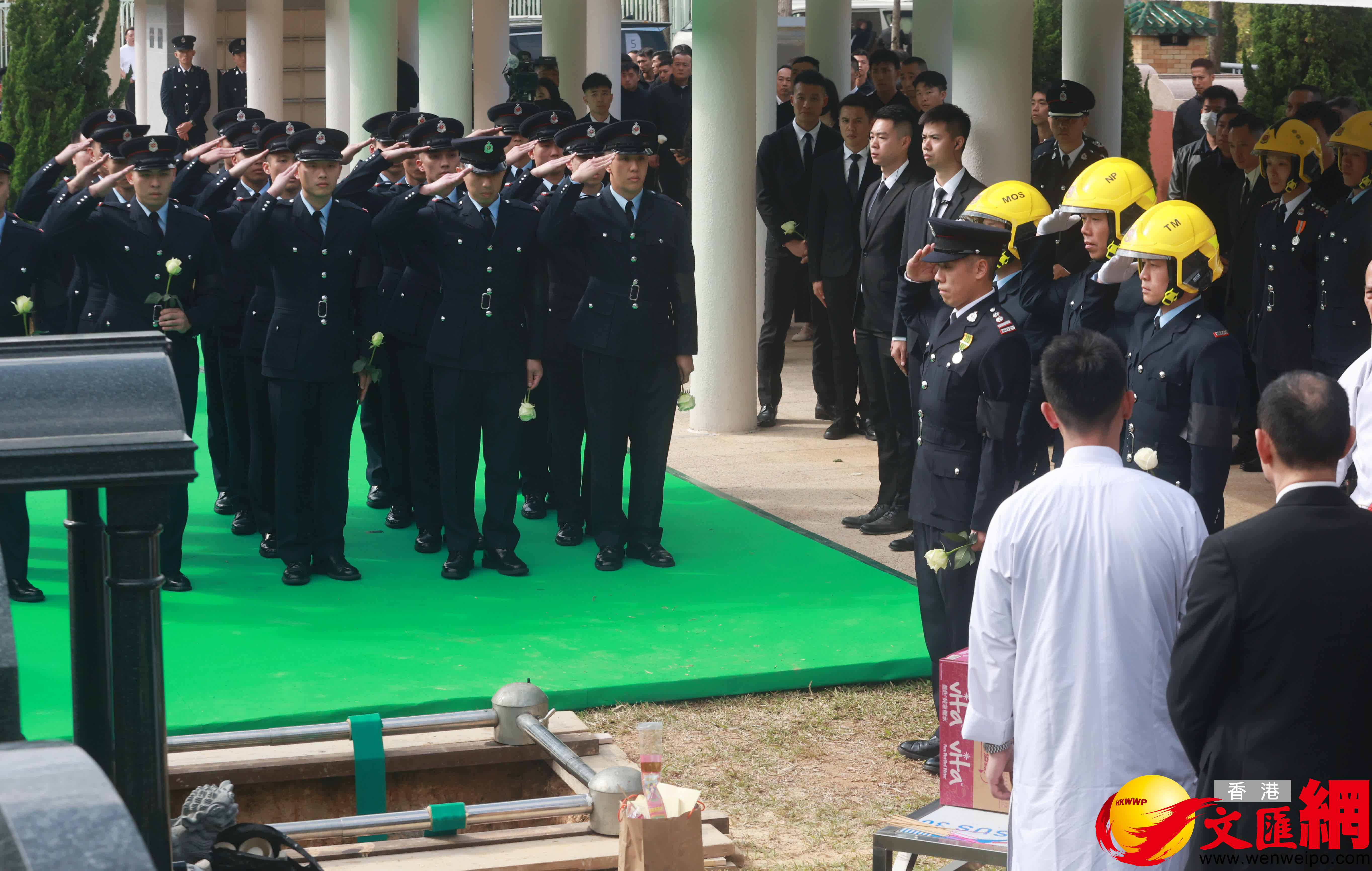 當靈柩被送下墓穴，親友及同袍最後輪流上前獻花，鞠躬致意。（香港文匯報記者郭木又攝）