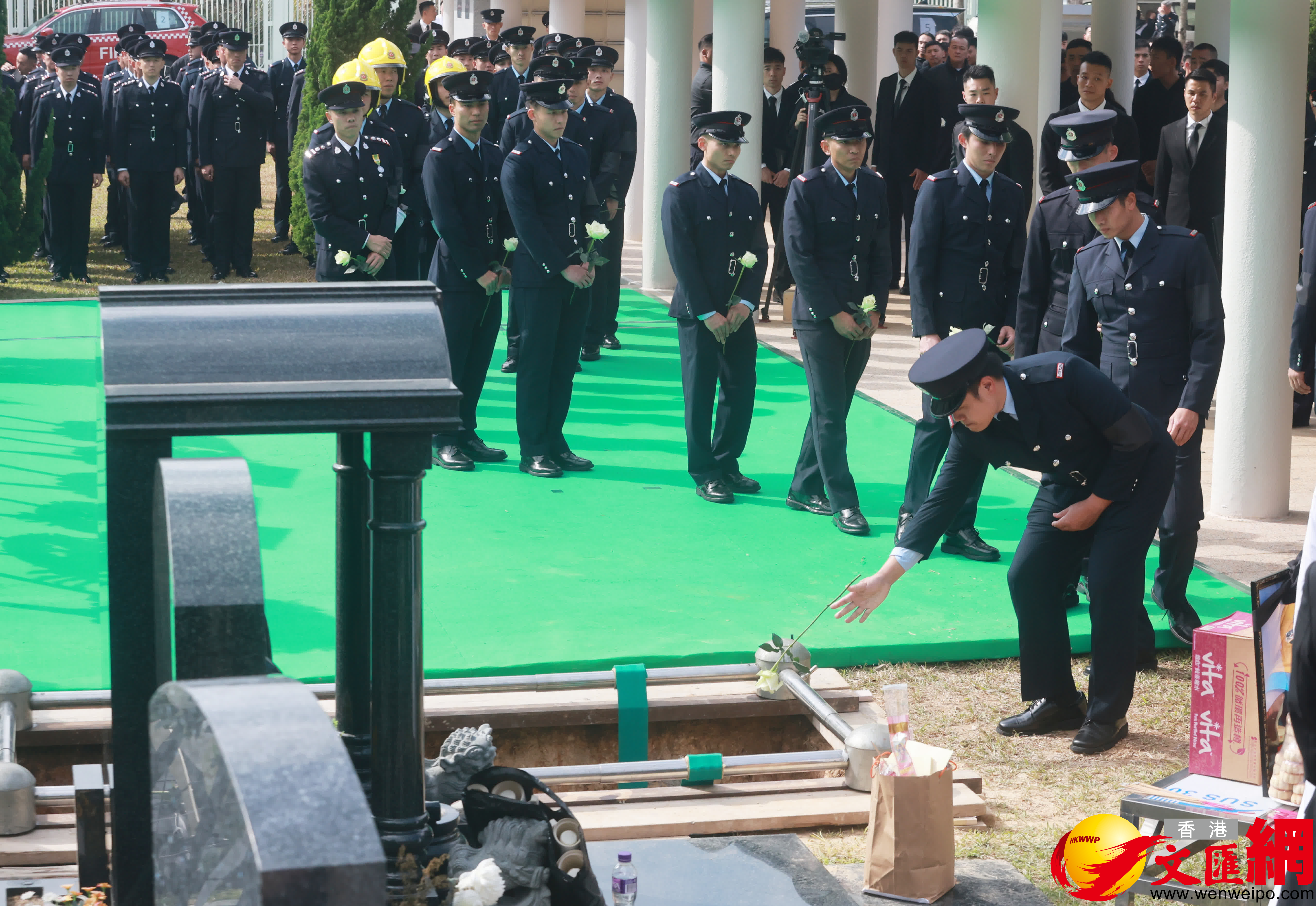 當靈柩被送下墓穴，親友及同袍最後輪流上前獻花，鞠躬致意。（香港文匯報記者郭木又攝）