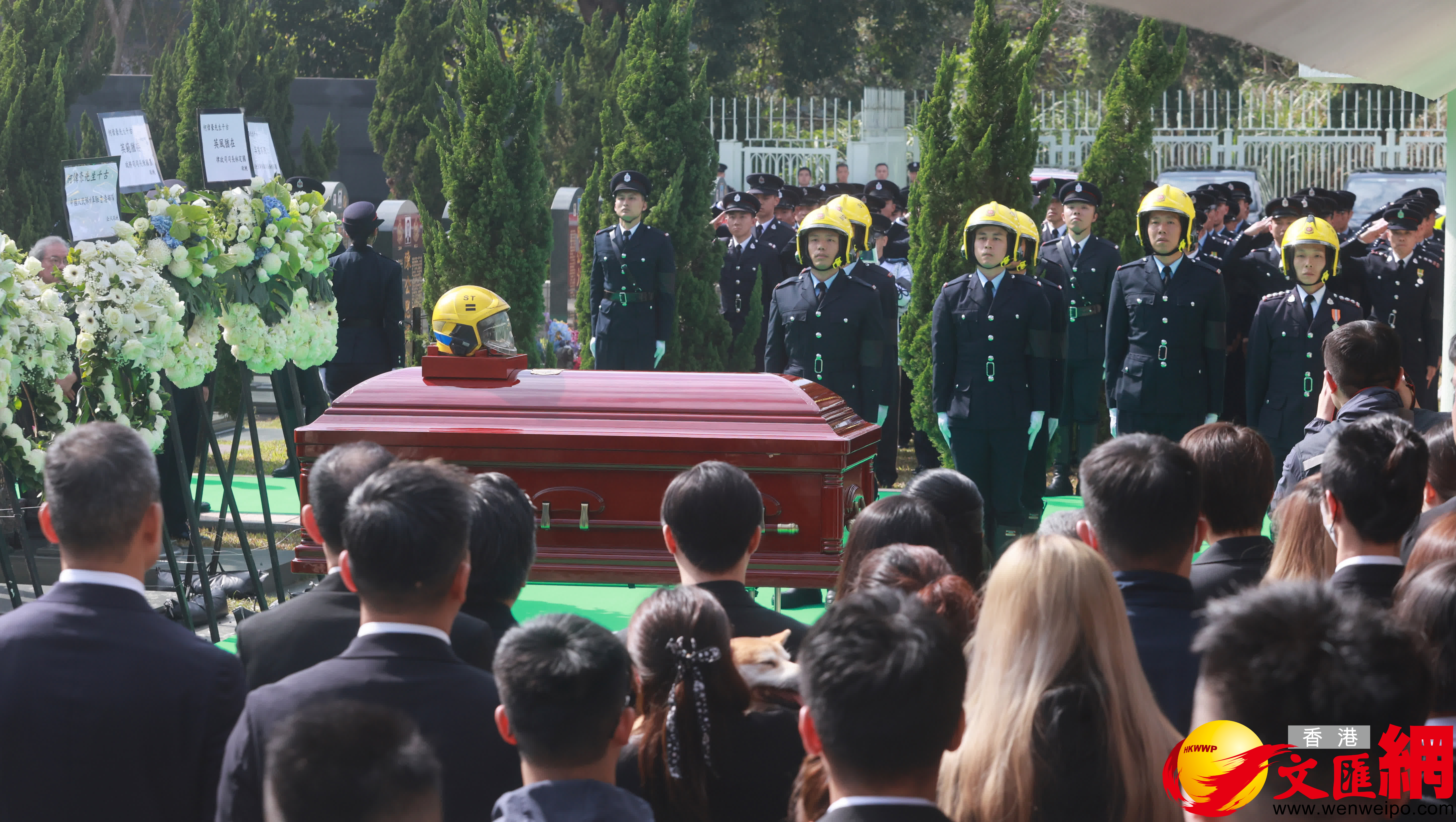 消防人員將何偉豪生前使用的消防頭盔擺放靈柩後，靈柩由工作人員移至墓穴下葬。（香港文匯報記者郭木又攝）