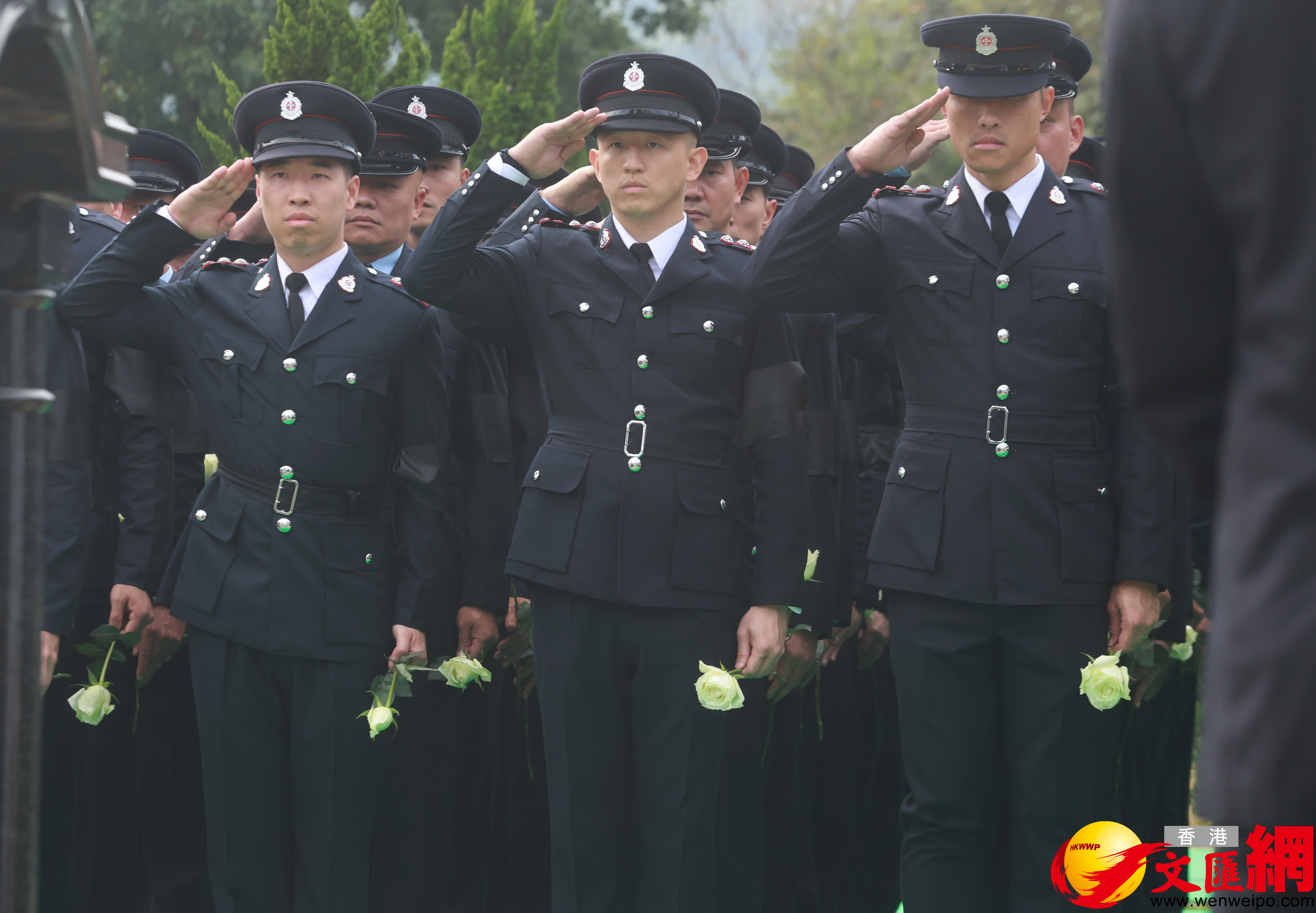 當靈柩被送下墓穴，親友及同袍最後輪流上前獻花，鞠躬致意。（香港文匯報記者郭木又攝）