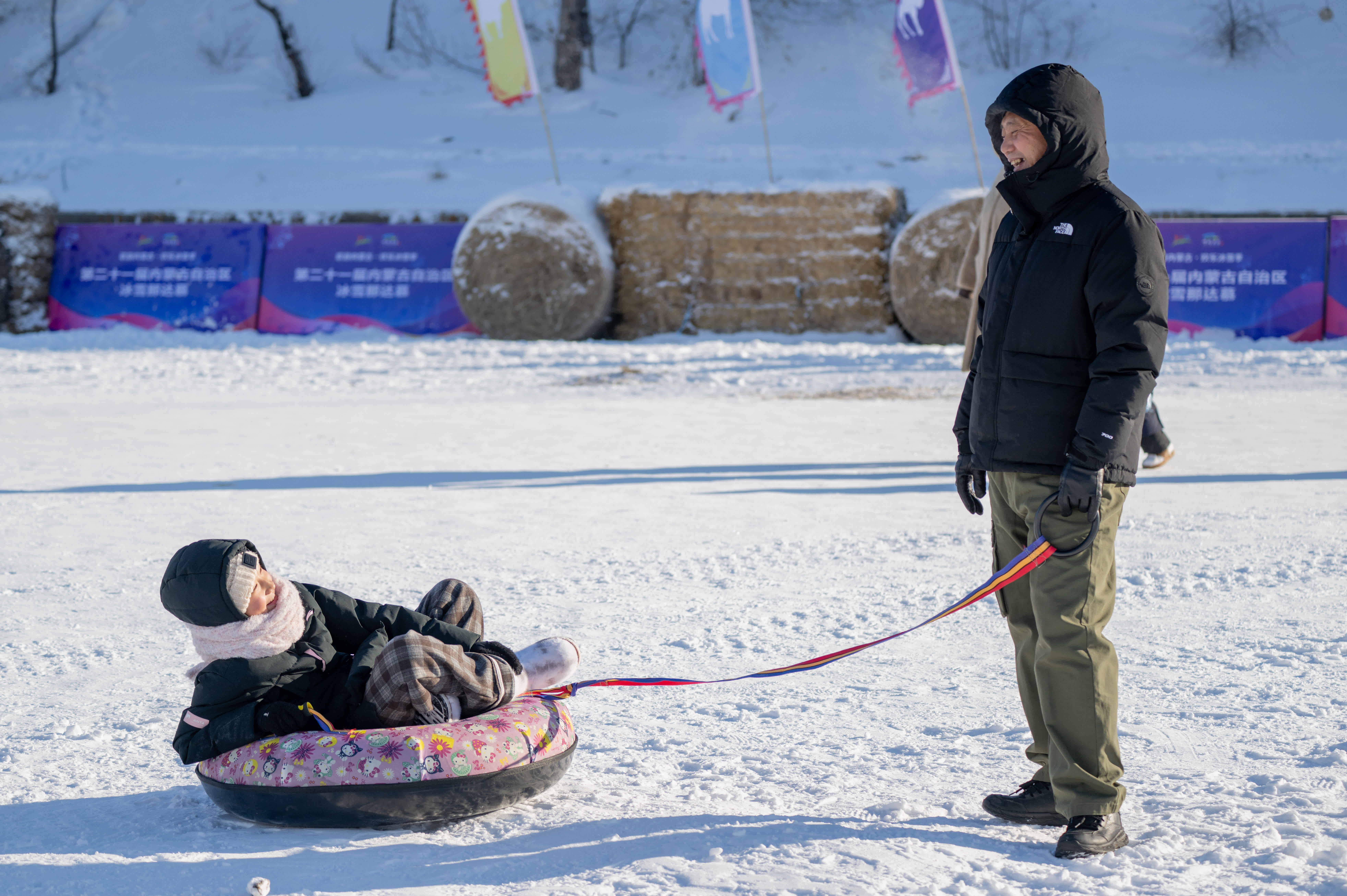 12月21日，一名市民帶着孩子在冰雪那達慕開幕式上玩耍。（新華社）
