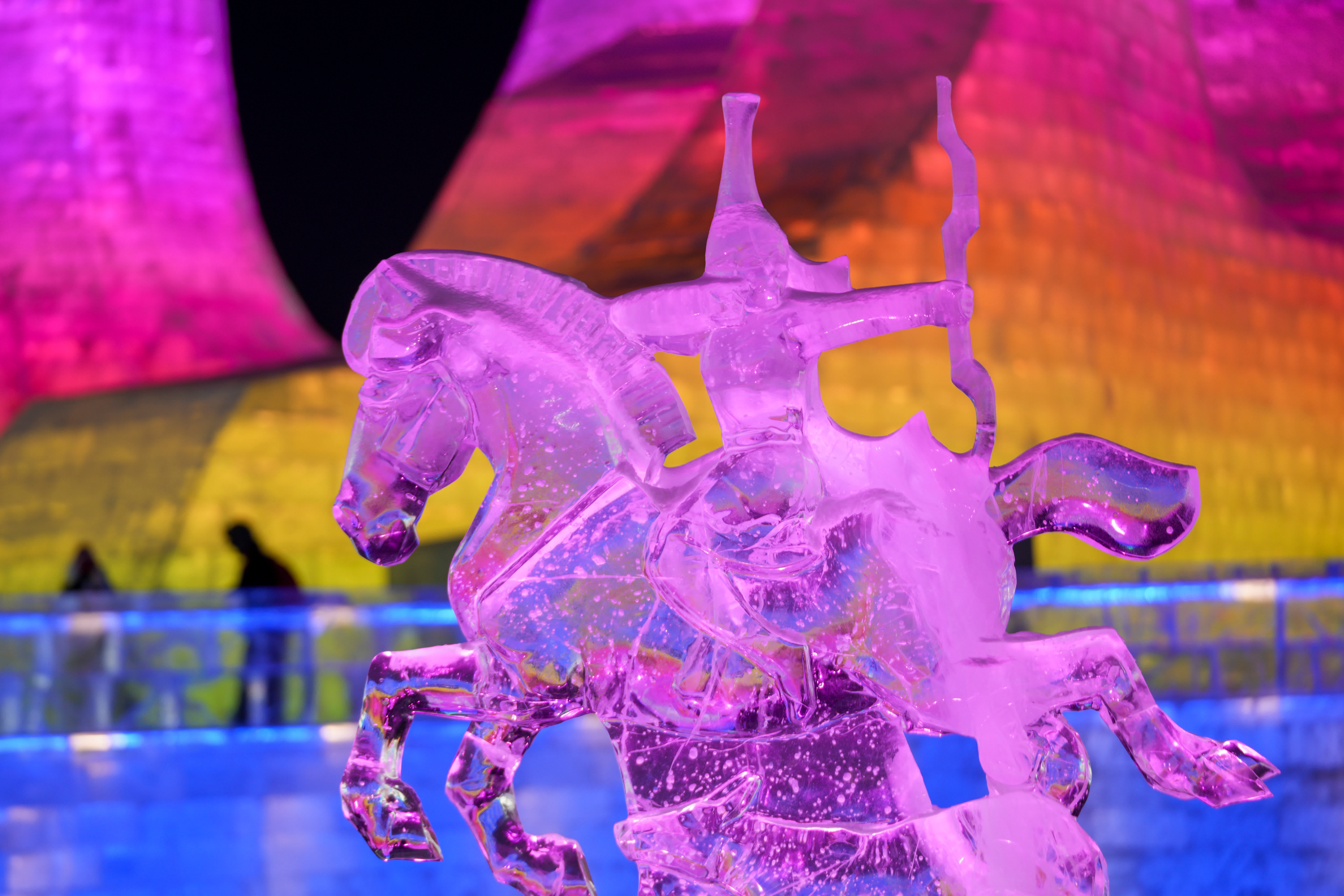 1月13日，遊客在哈爾濱冰雪大世界園區內的冰雕作品《馬到成功》附近遊玩。（新華社）