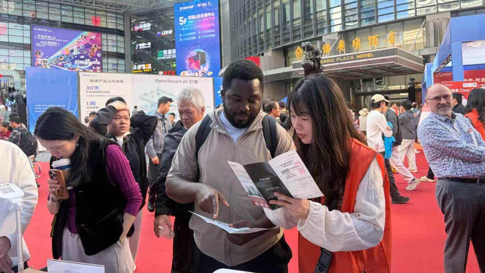 （有片）廣交會客商深圳「跨國掃貨」　志願者以AI翻譯機服務外籍顧客